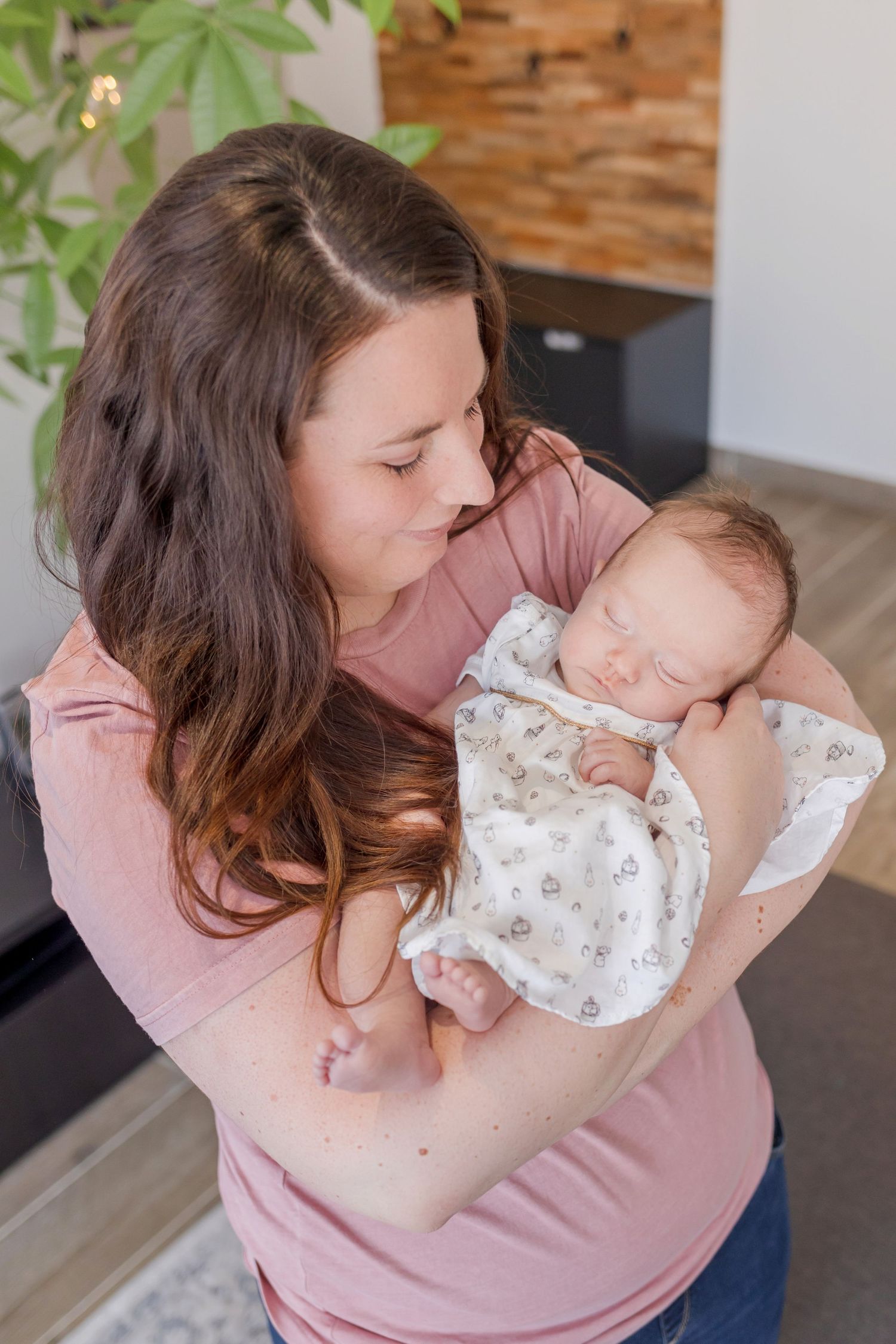 Tender moments of a baby being cradled and cuddled while wearing a delicate white outfit.