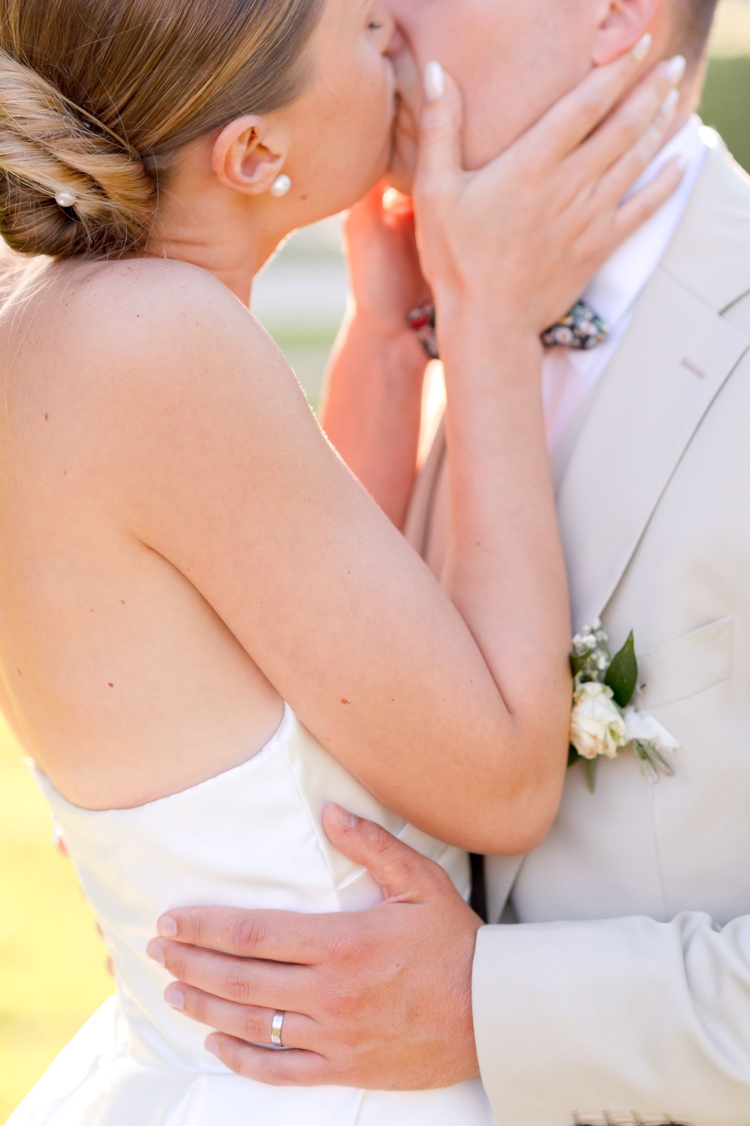 Romantic wedding couple embrace in soft golden sunlight.