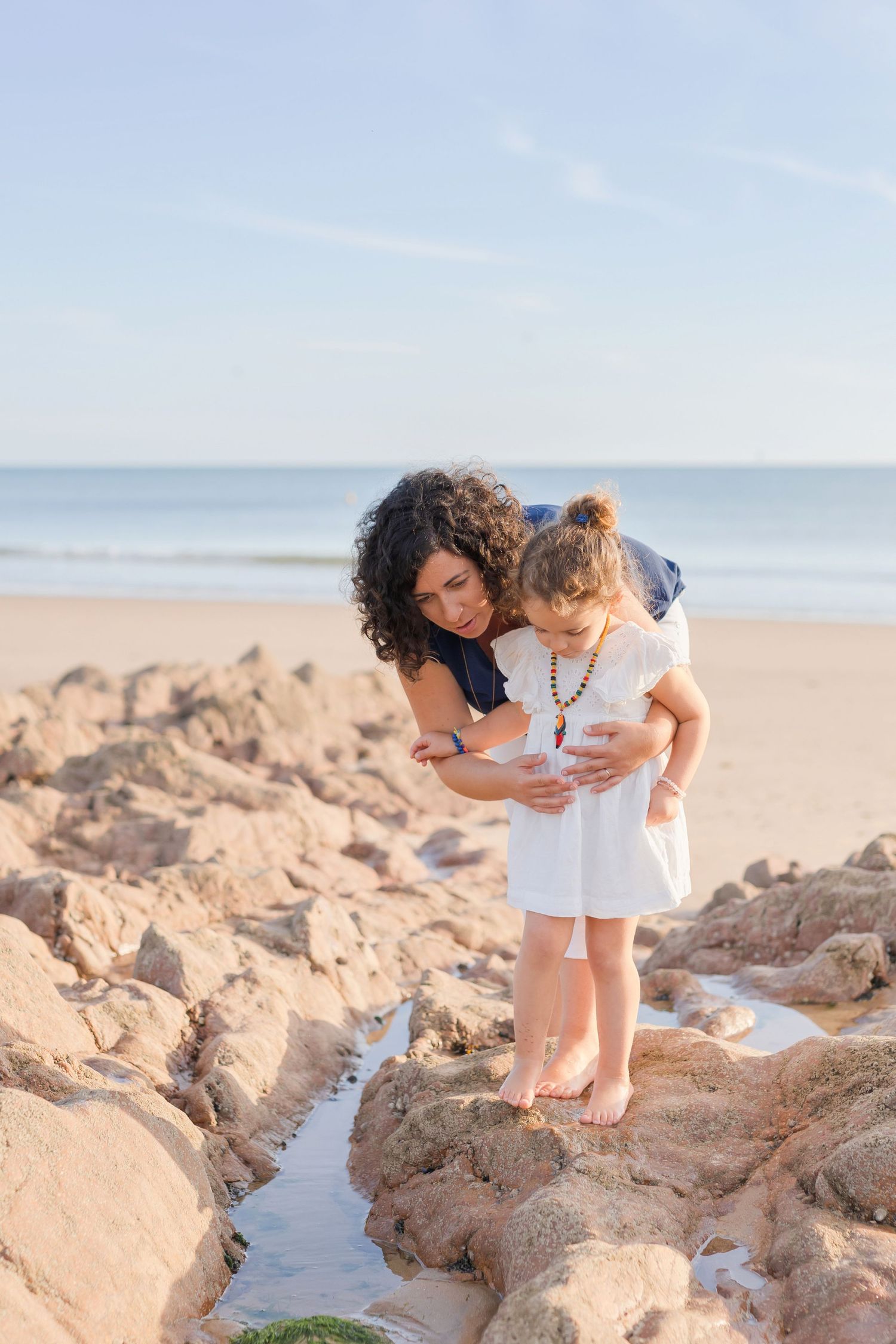 A heartwarming moment exploring tidal pools on rocky beach formations.