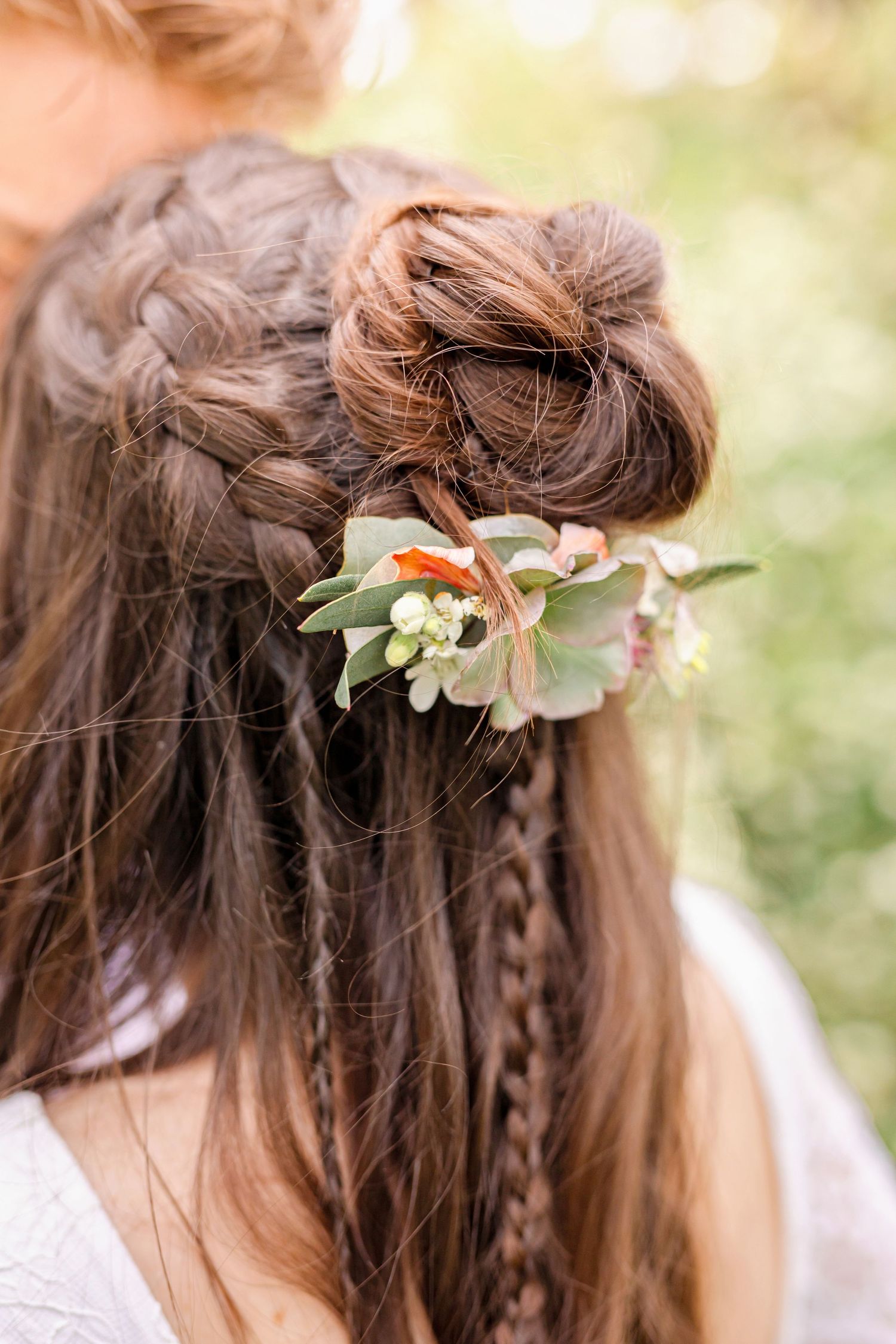Detailed view of bridal hairstyle featuring braids and delicate floral hair accessories.