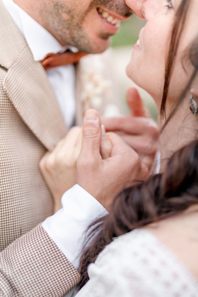 Close up of a romantic moment between newlyweds embracing in formal wedding attire.