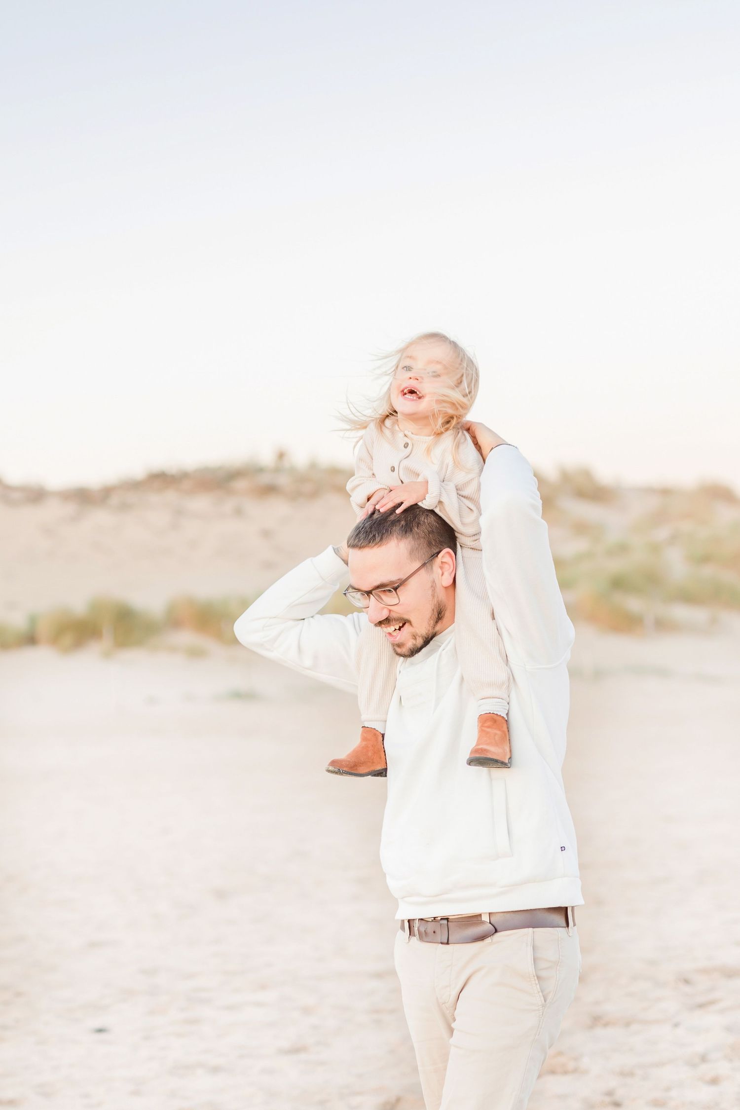 Parent and child playing together on a sandy beach at sunset.