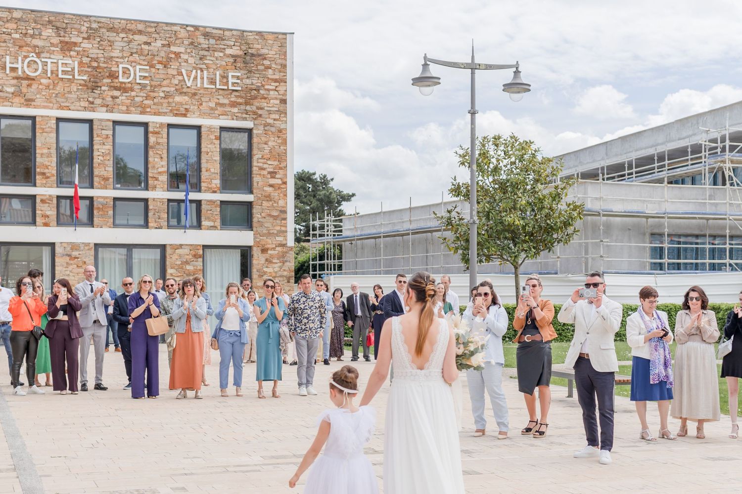 Wedding guests and bridal party lined up for group photo outside brick building.