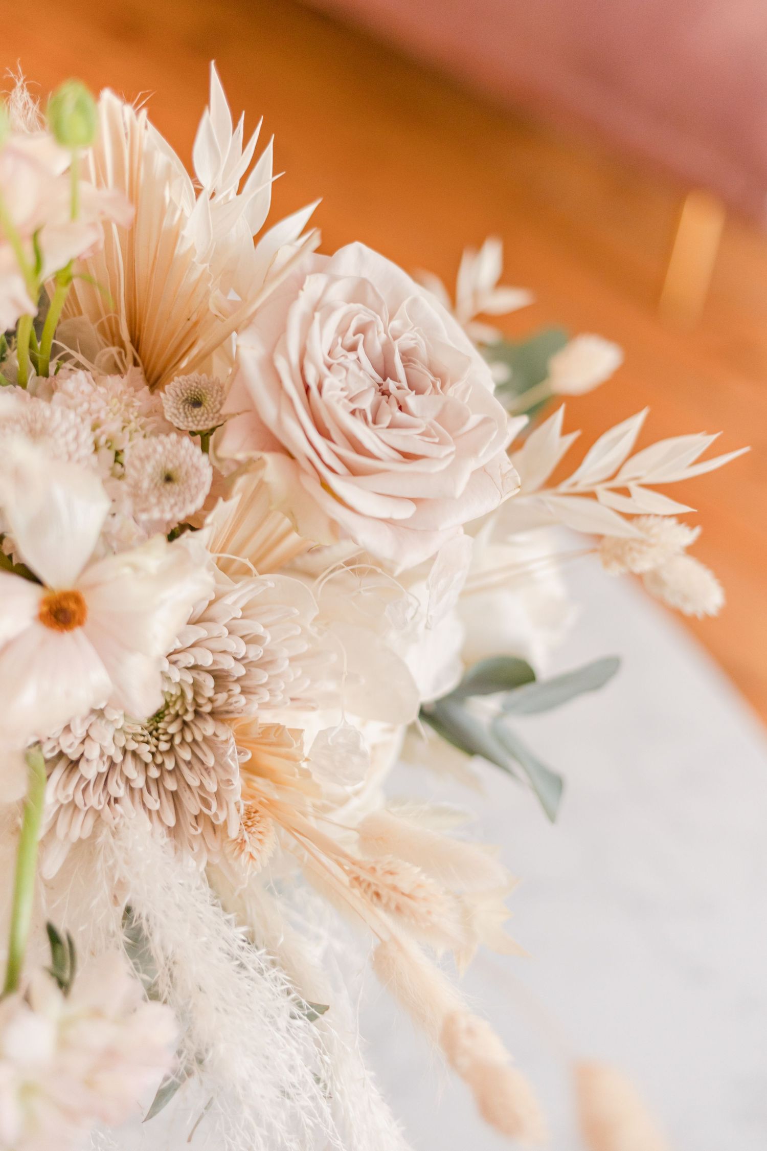 Close-up of pale pink roses and dried flowers in romantic wedding arrangement.