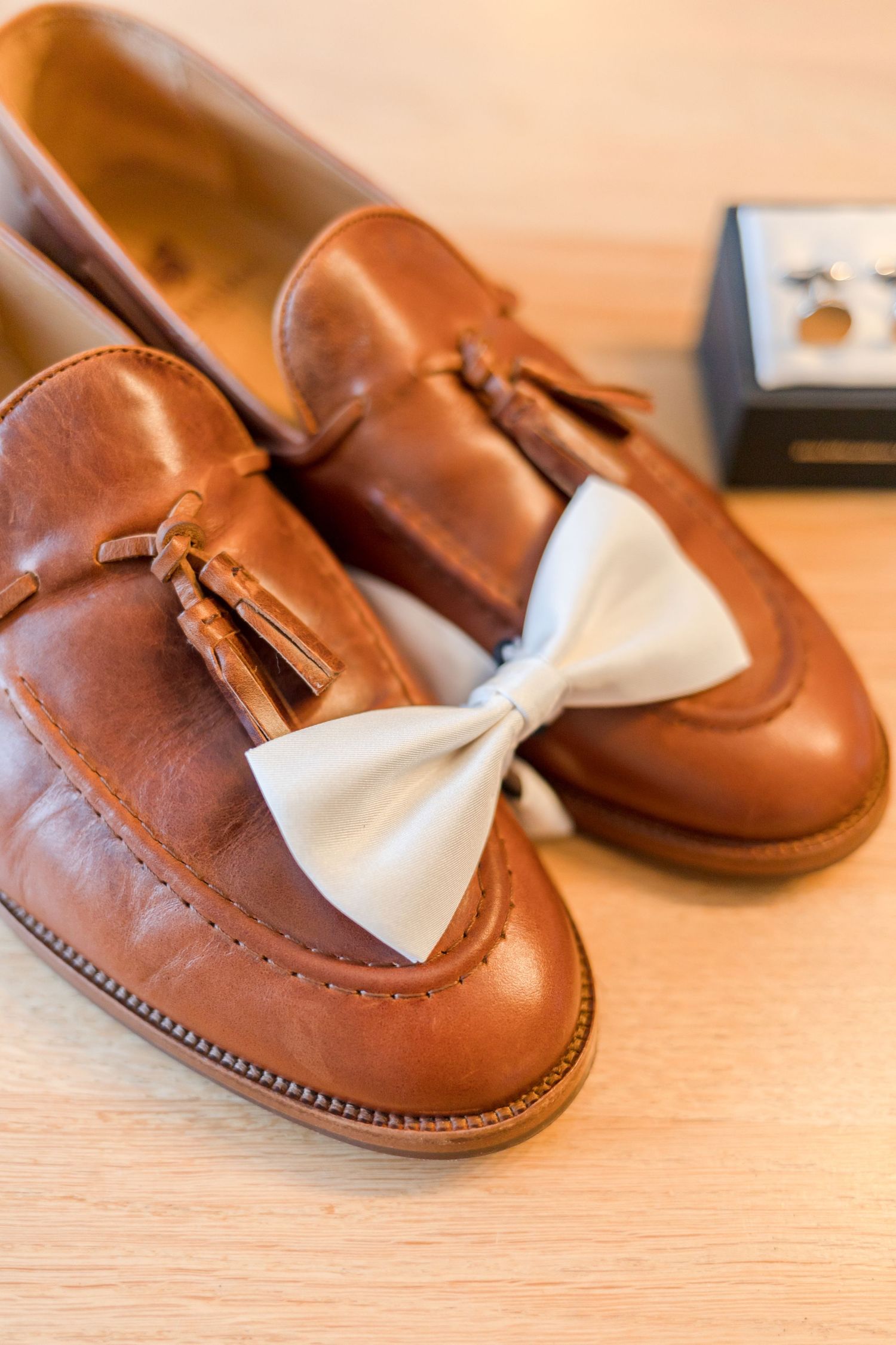 Brown leather dress shoes with white bow ties arranged for wedding day preparation.