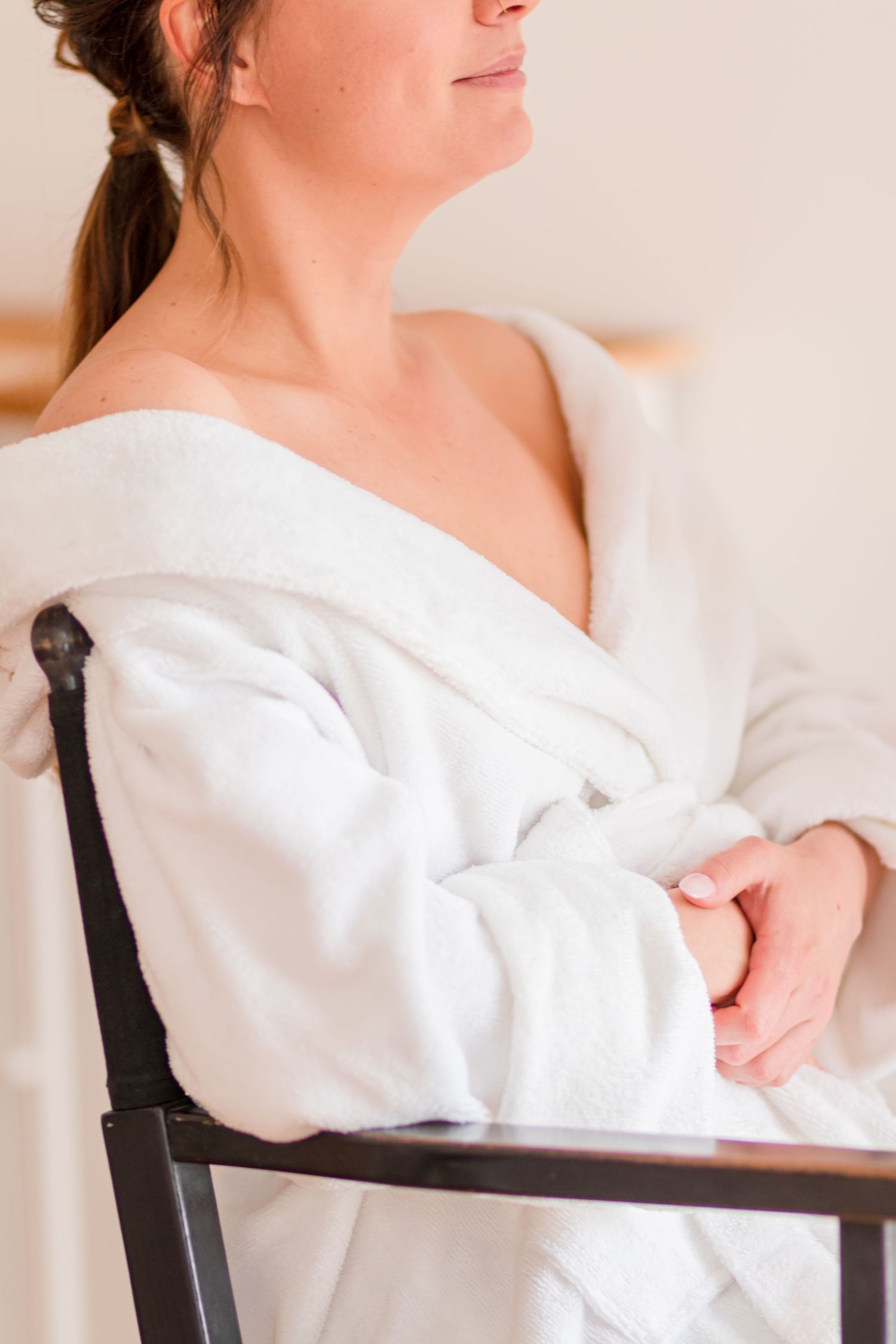 Person wearing a white robe sits elegantly in a chair during preparation.