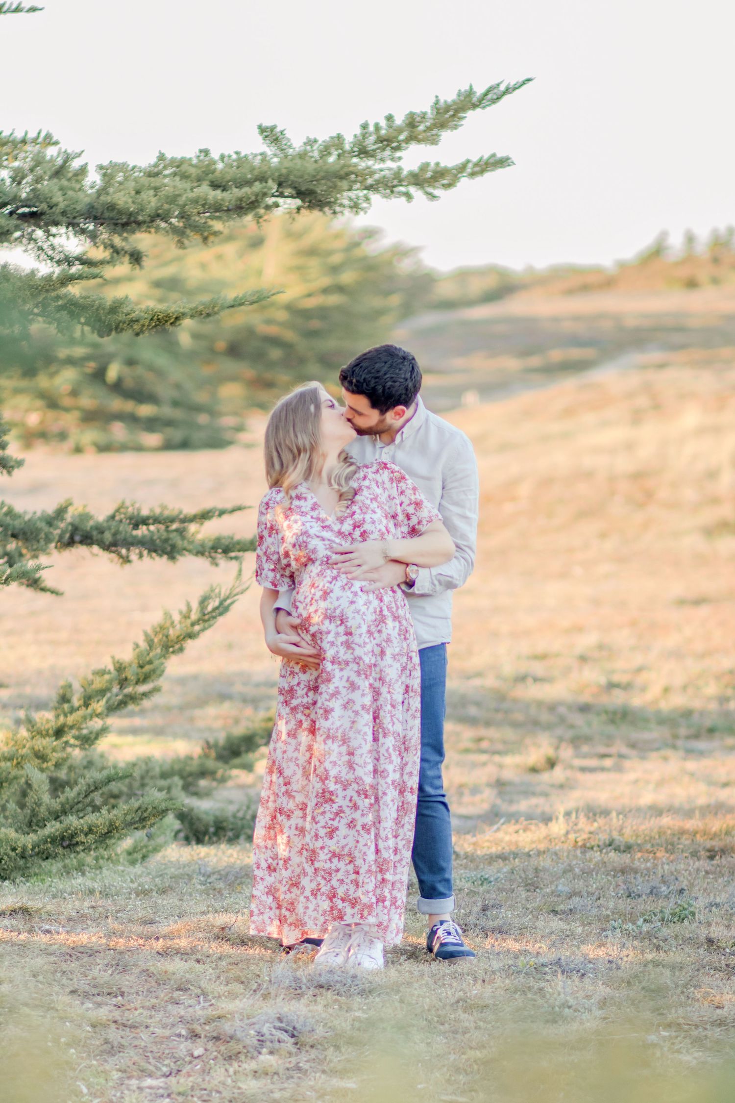 Romantic couple sharing intimate moment on hillside with evergreen trees.