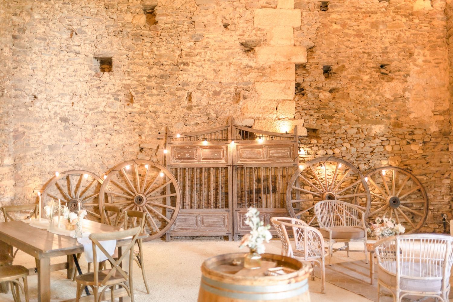 Rustic barn venue decorated with vintage wagon wheels and wooden chairs for a wedding reception.