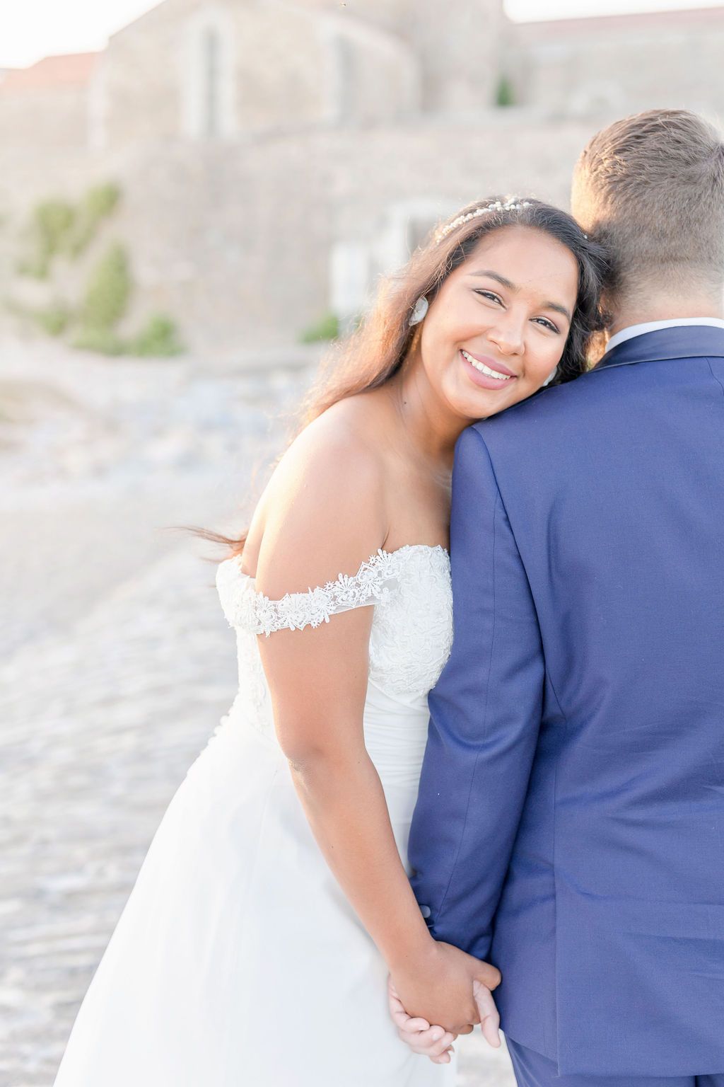 Intimate wedding photo capturing joyful moments between couple against stone architecture.