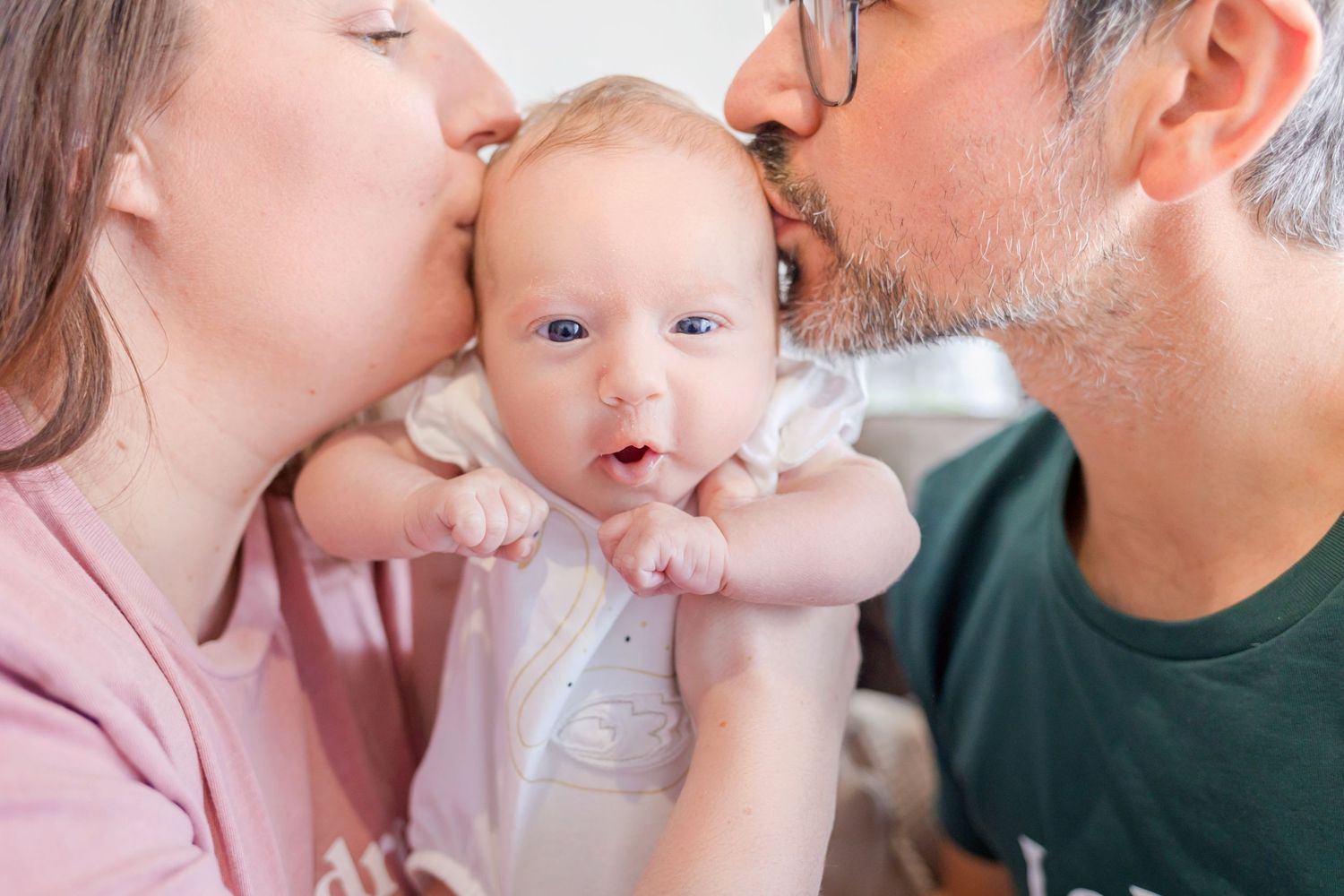 Sweet moments captured as family members share gentle kisses with a newborn baby.