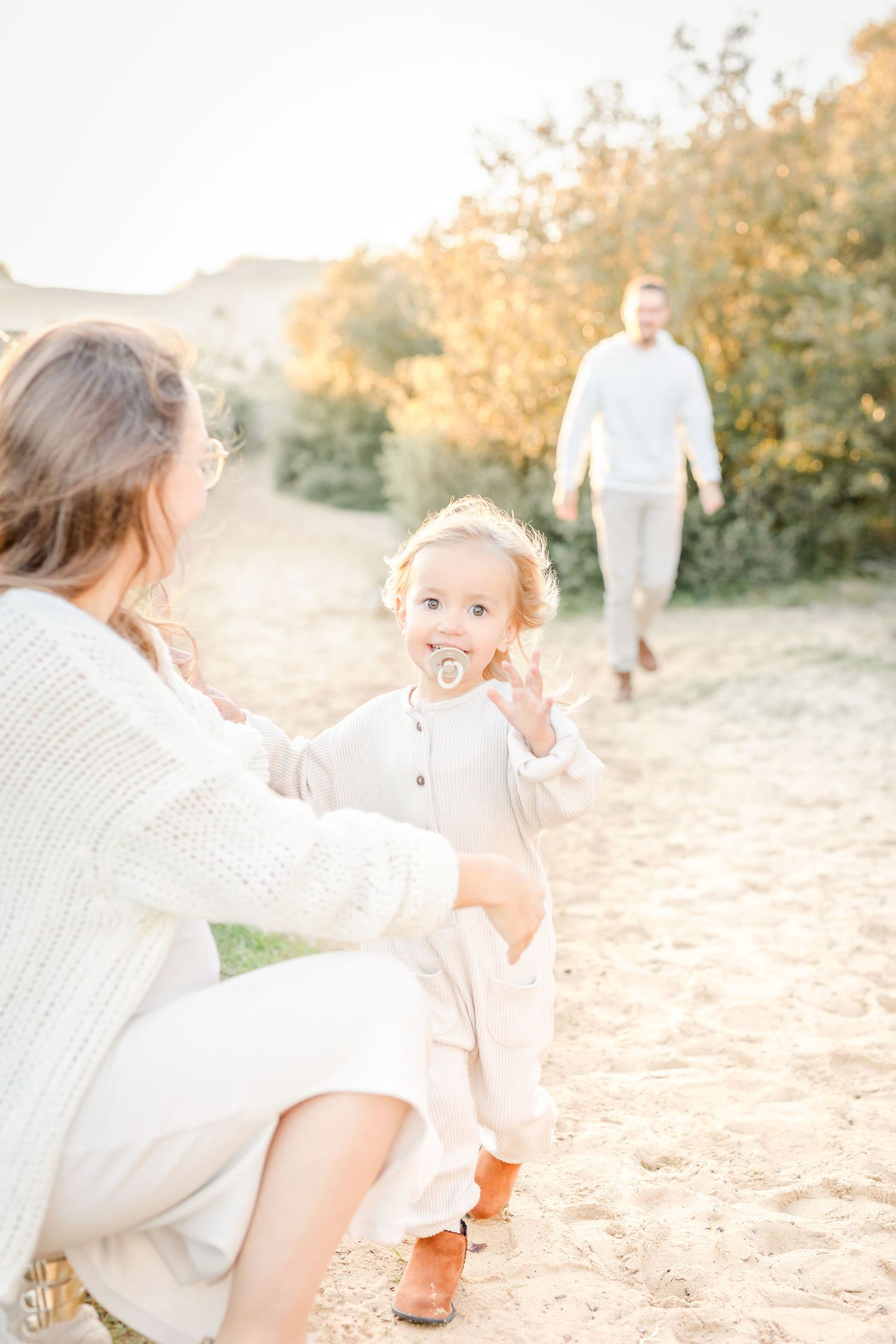 Family plays together on sandy path during sunset outdoor photography session.