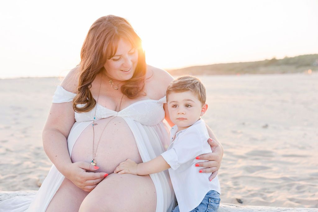 A tender beach portrait of mother and child sitting on sandy shore.