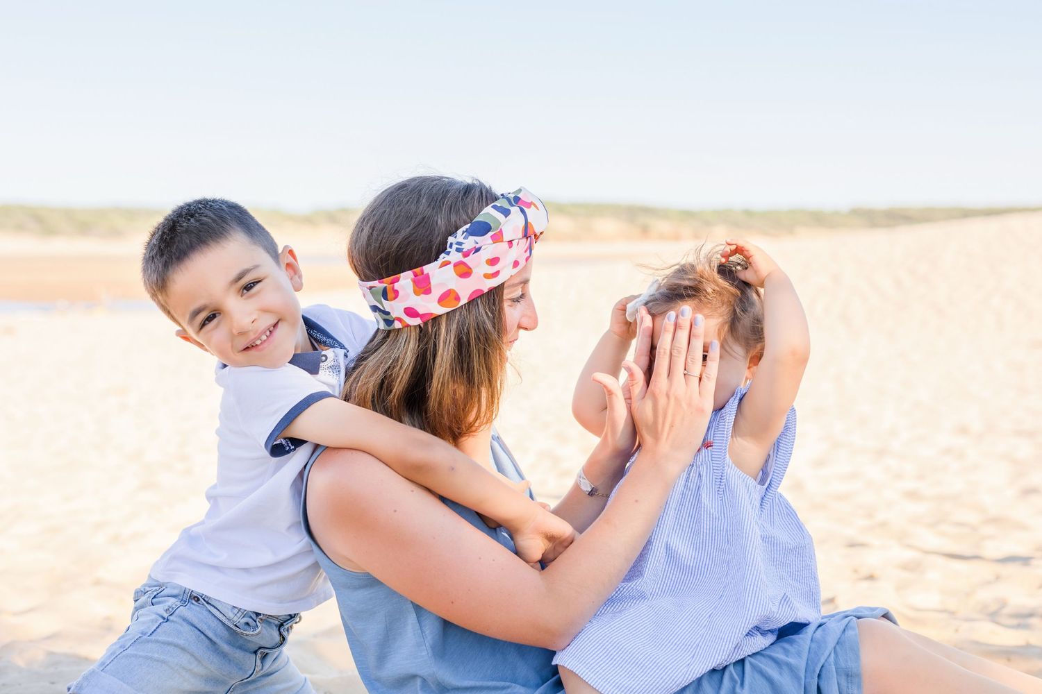 Candid family photo session at the beach with coordinated blue and white outfits.