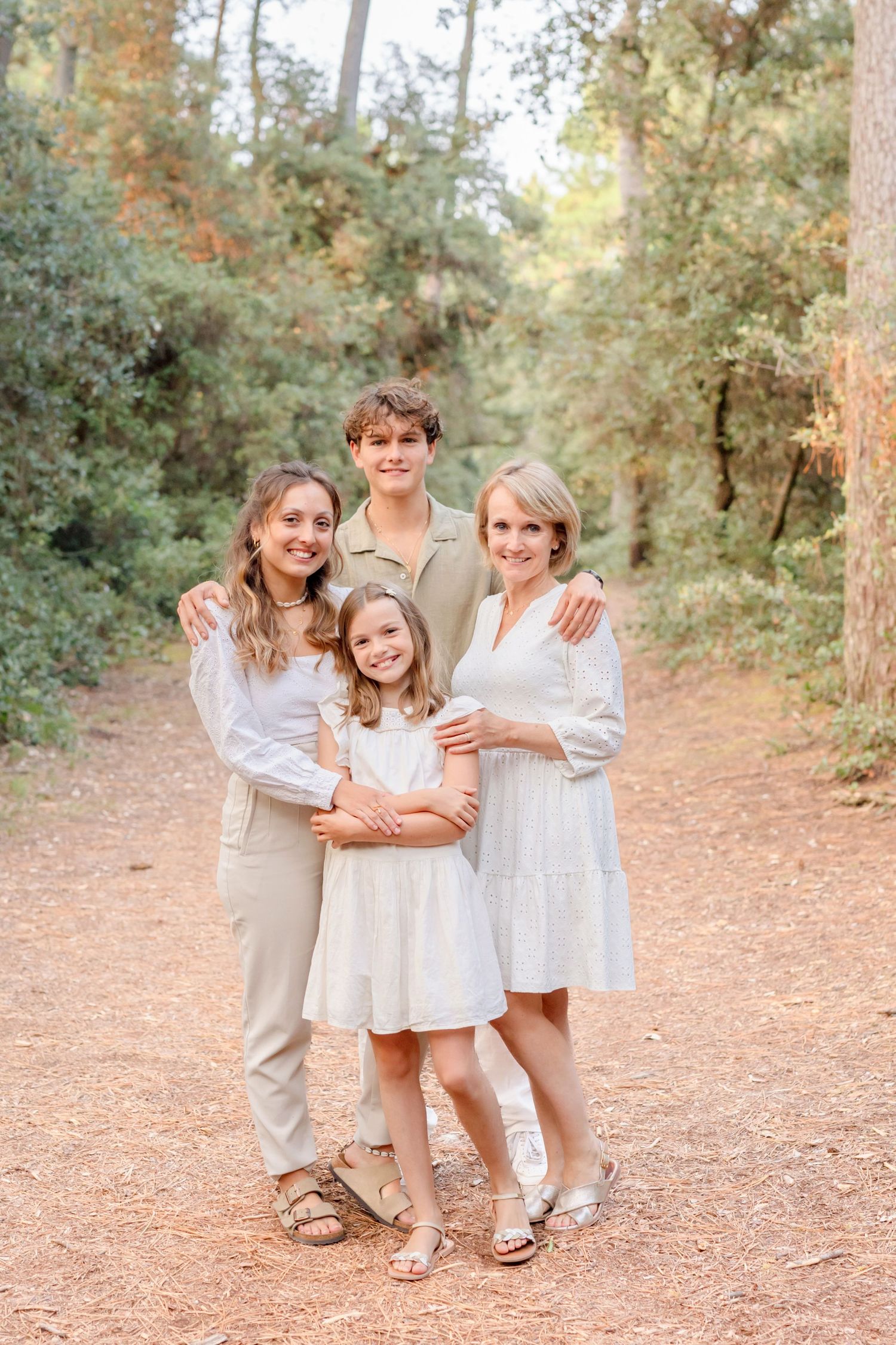 Family portrait on a scenic forest trail with everyone dressed in light neutral colors.