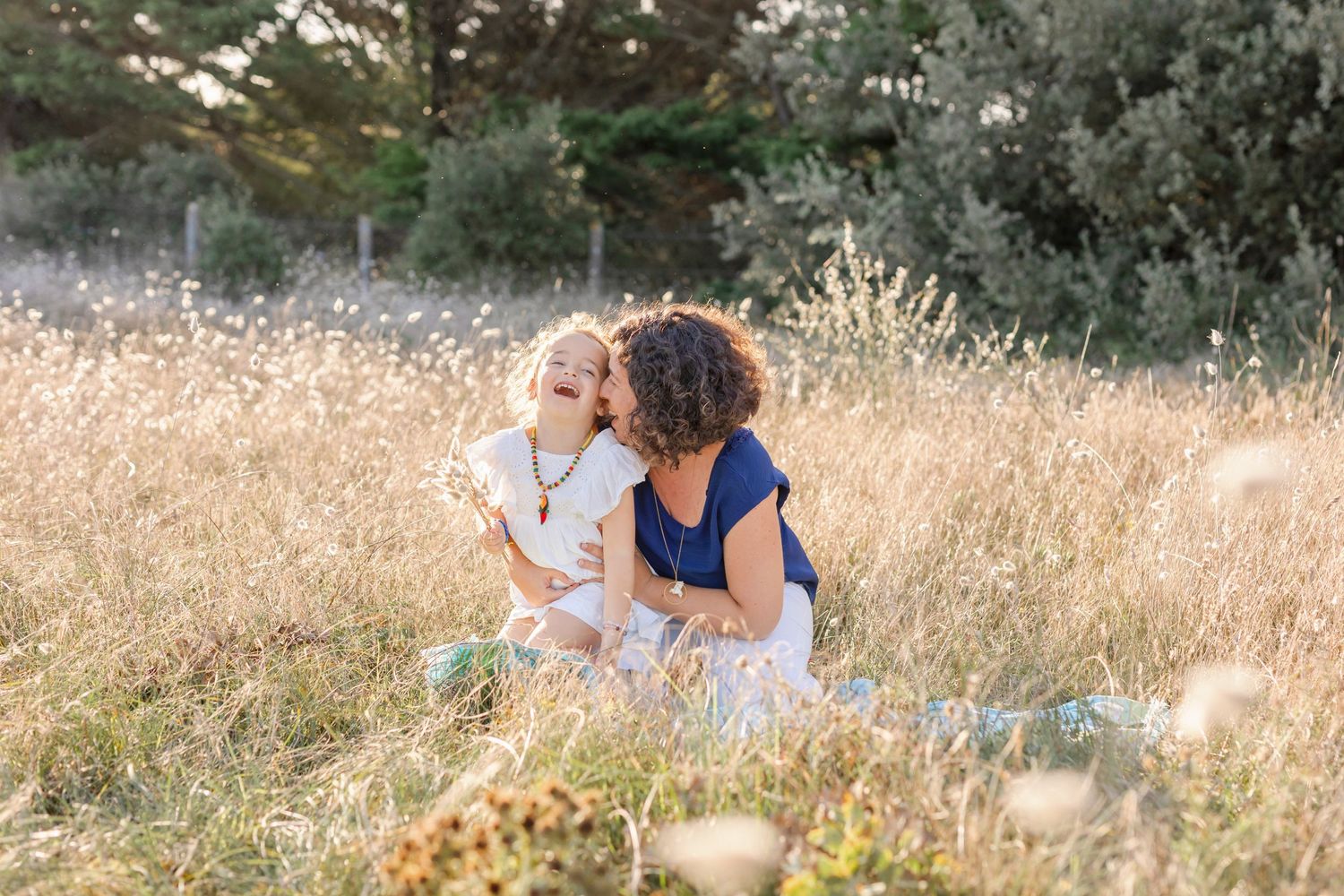 Tender moment between parent and child in golden summer field.