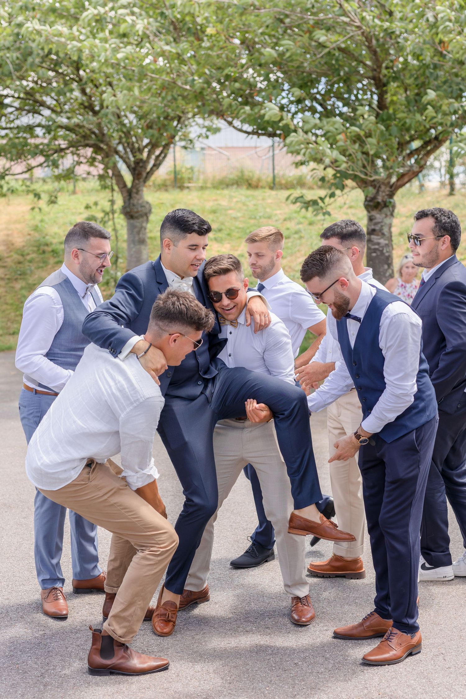 Groomsmen in formal attire having fun posing together on pathway.
