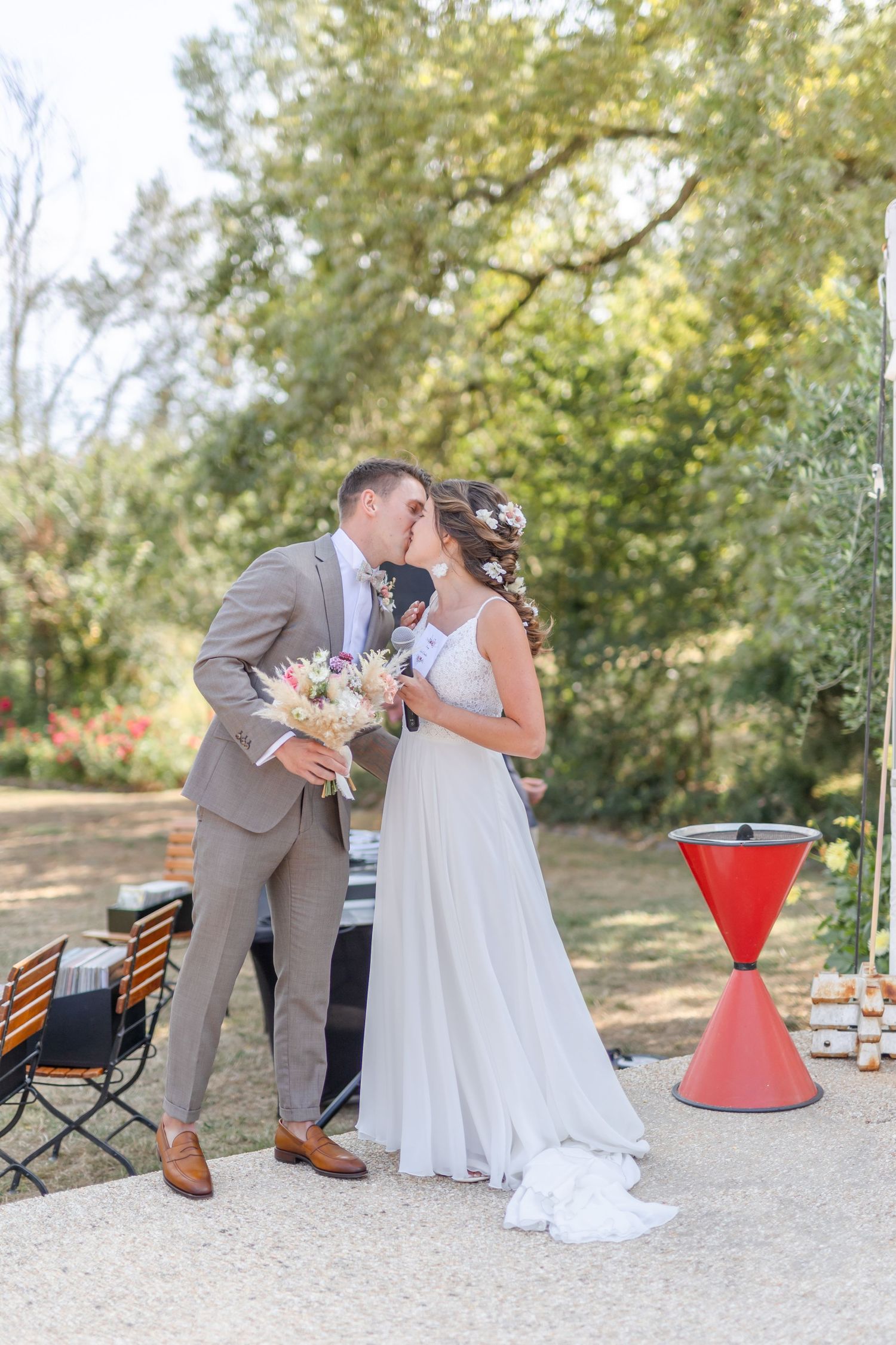 Outdoor wedding reception area with red cocktail tables and natural decor.