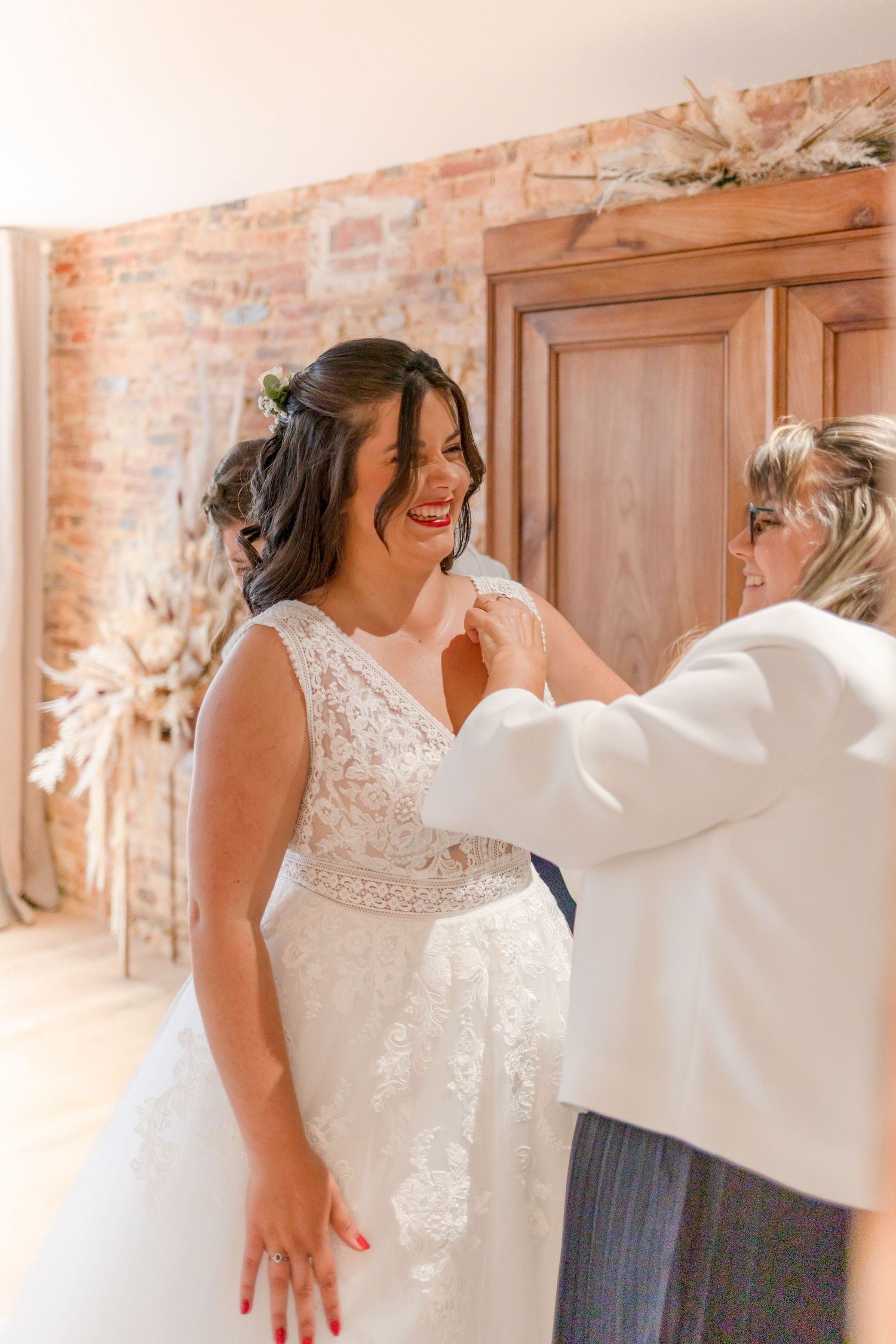 Emotional moment during wedding dress fitting with bridesmaid helping the bride.
