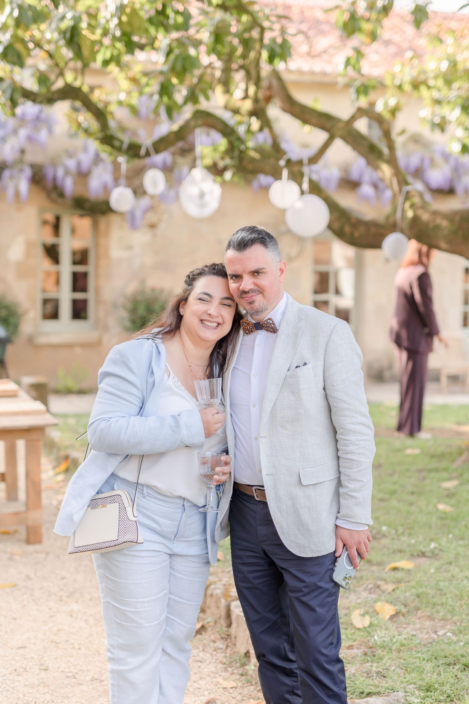 Couple in coordinated light blue and grey outfits posing outdoors near flowering trees.
