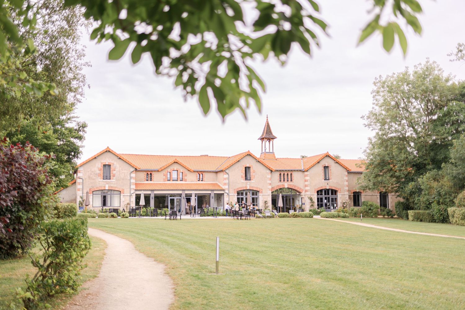 Sprawling French country estate with terra cotta roof and bell tower on landscaped grounds.