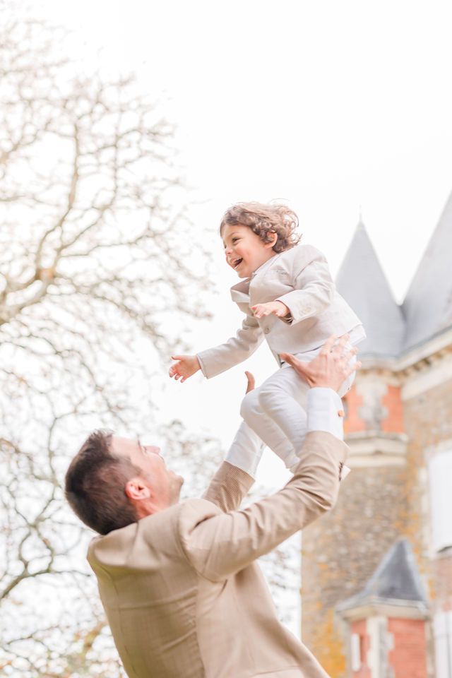 Joyful lifting pose captured against historic building with autumn trees in background.