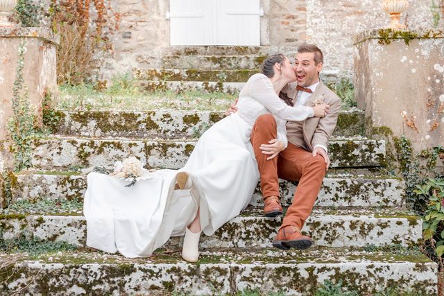 Newlyweds share a joyful moment on rustic stone steps with a white dress flowing.