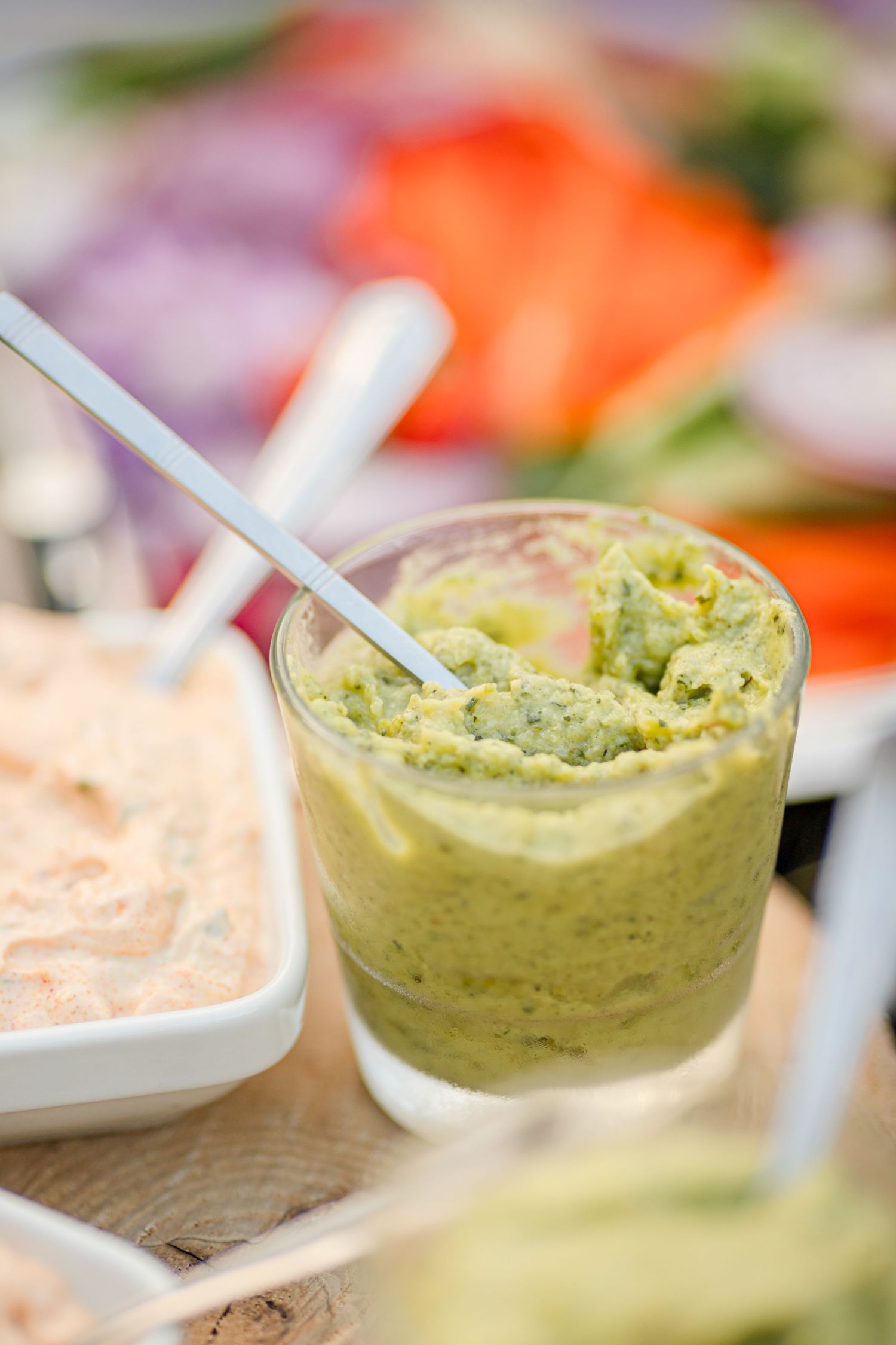 Green avocado-based dip served in a glass with a white straw.