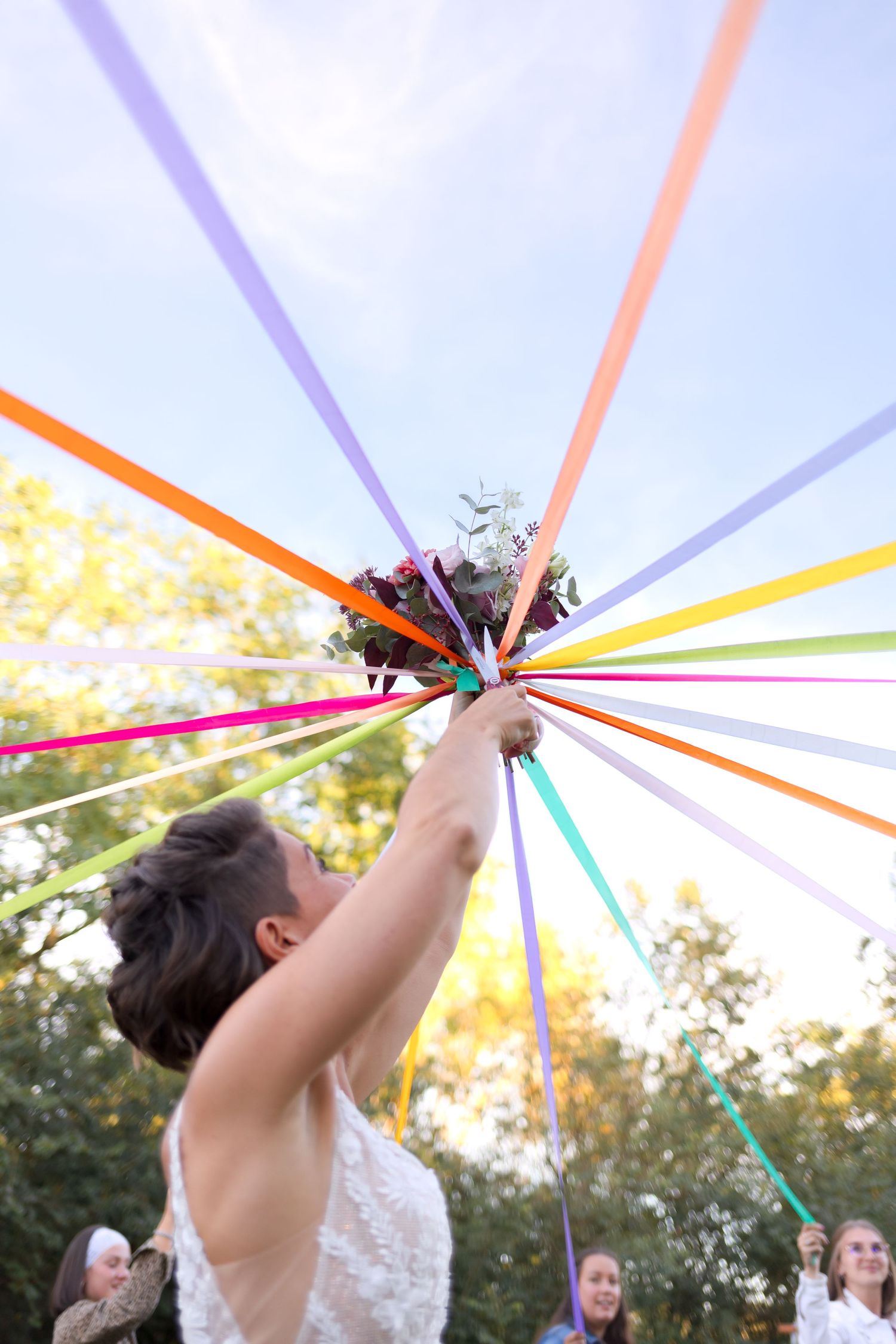 Colorful ribbons radiating from a central point against a bright blue sky at an outdoor celebration.