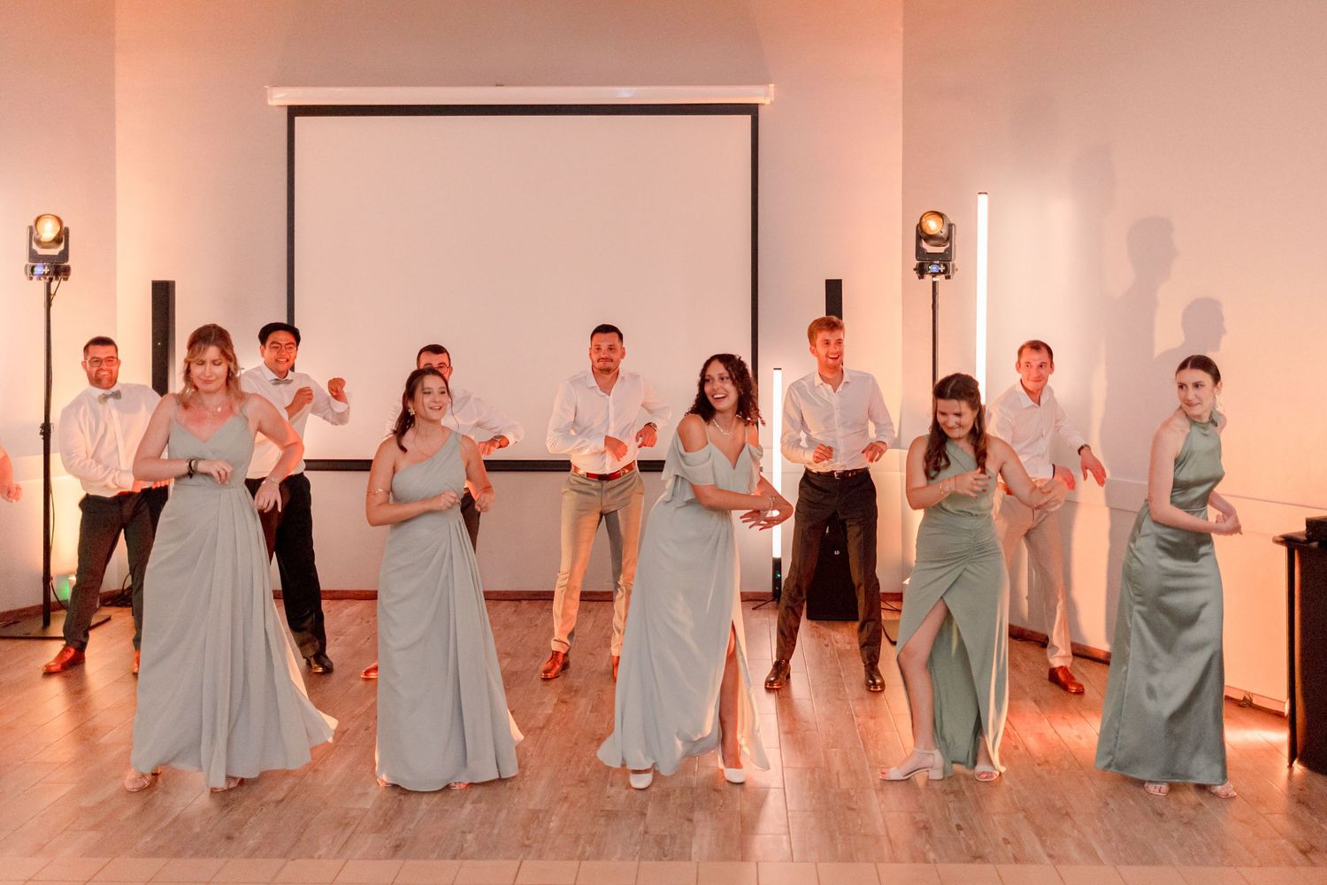 Wedding party poses in light blue bridesmaid dresses on stage during reception.