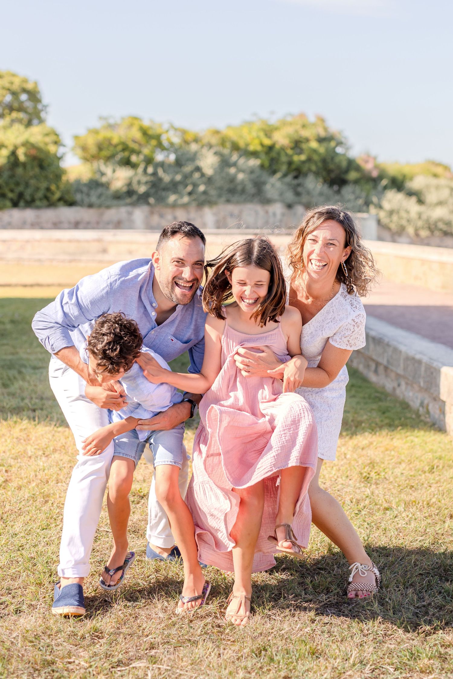 Group playing and laughing together on grassy hill during sunset photoshoot.