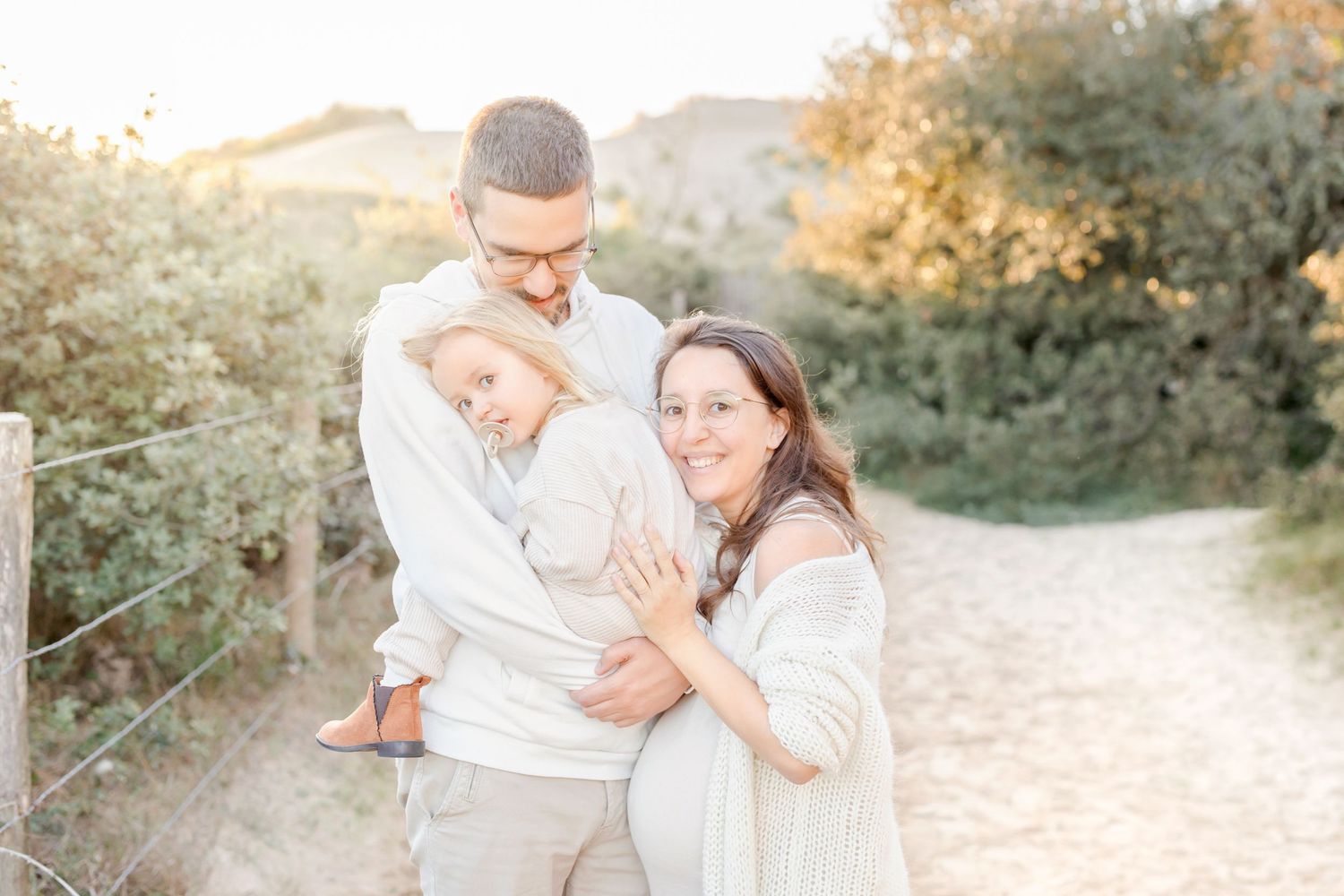 Family sharing tender embrace outdoors during golden hour portrait session.
