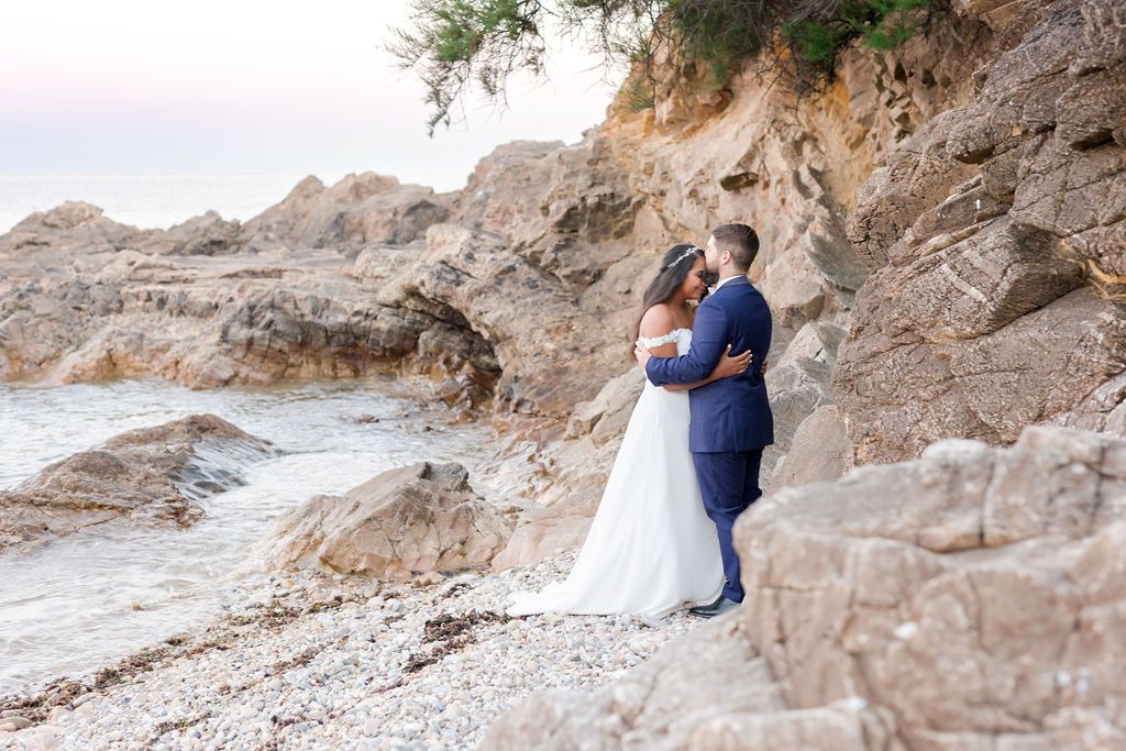 A romantic wedding photo captured against rugged coastal cliffs and ocean waves.