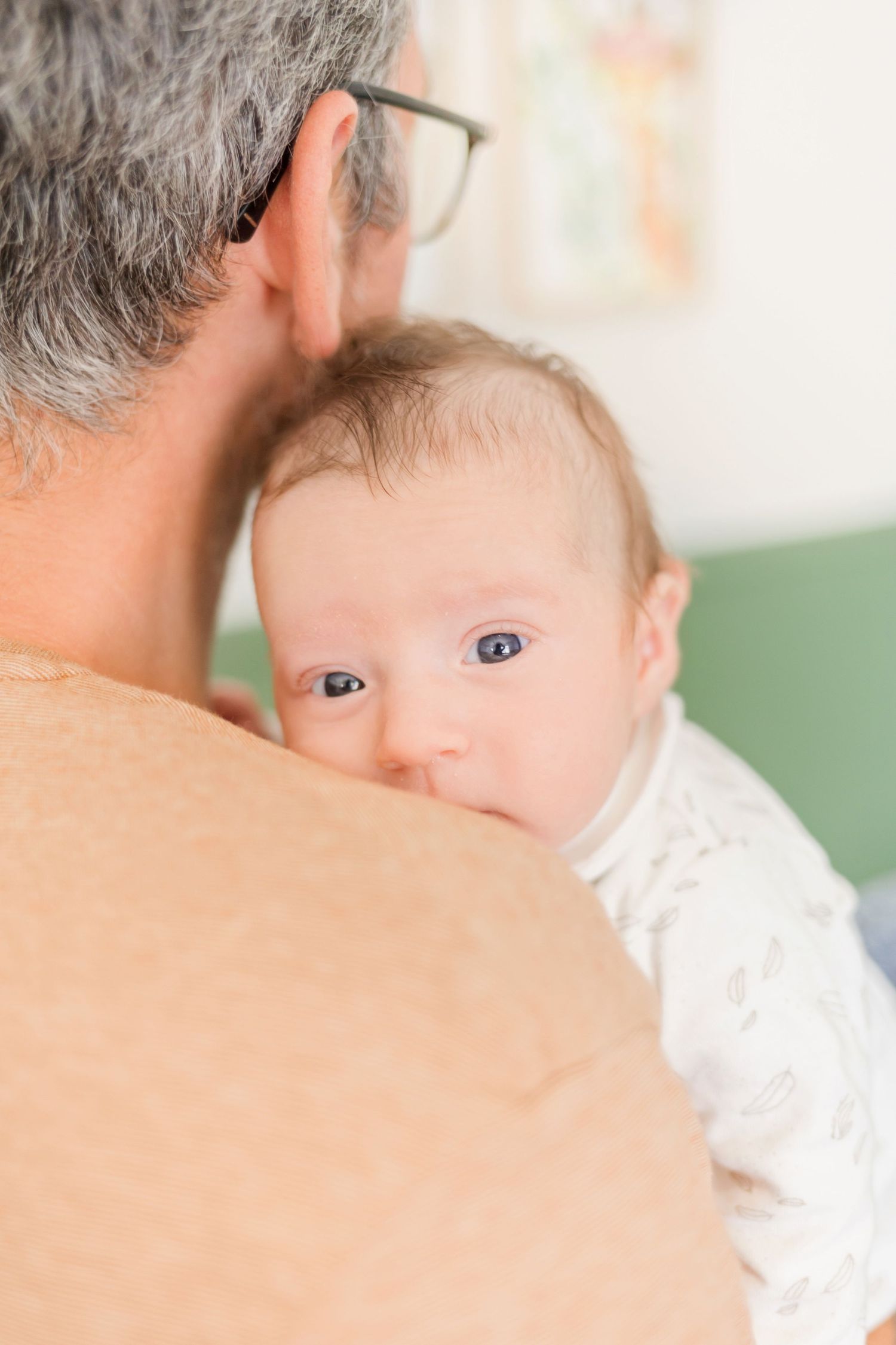 Close-up view of person wearing beige sweater holding infant.