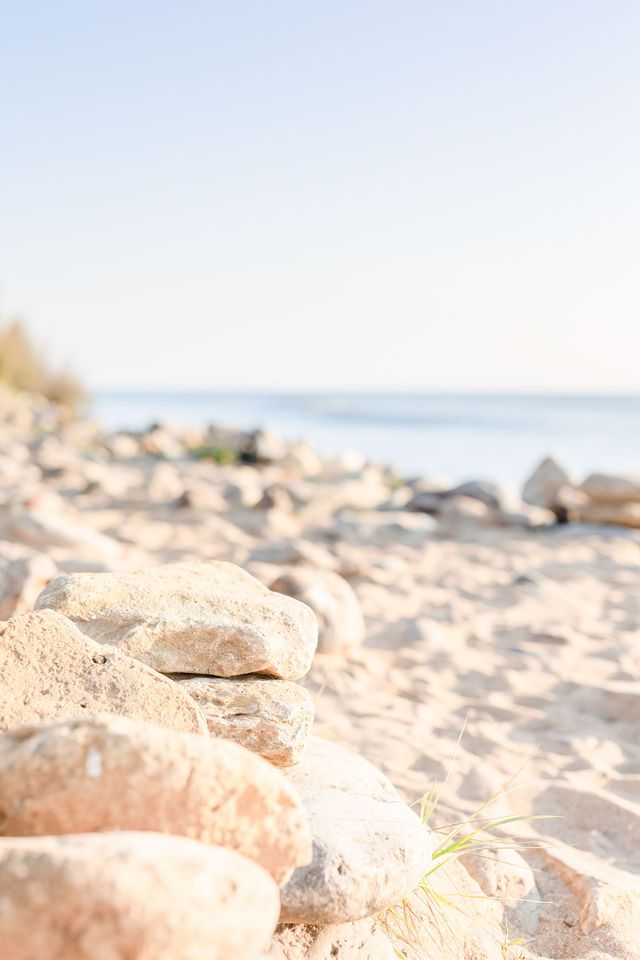 Rocky beach shoreline with stones in foreground and ocean horizon in soft morning light.