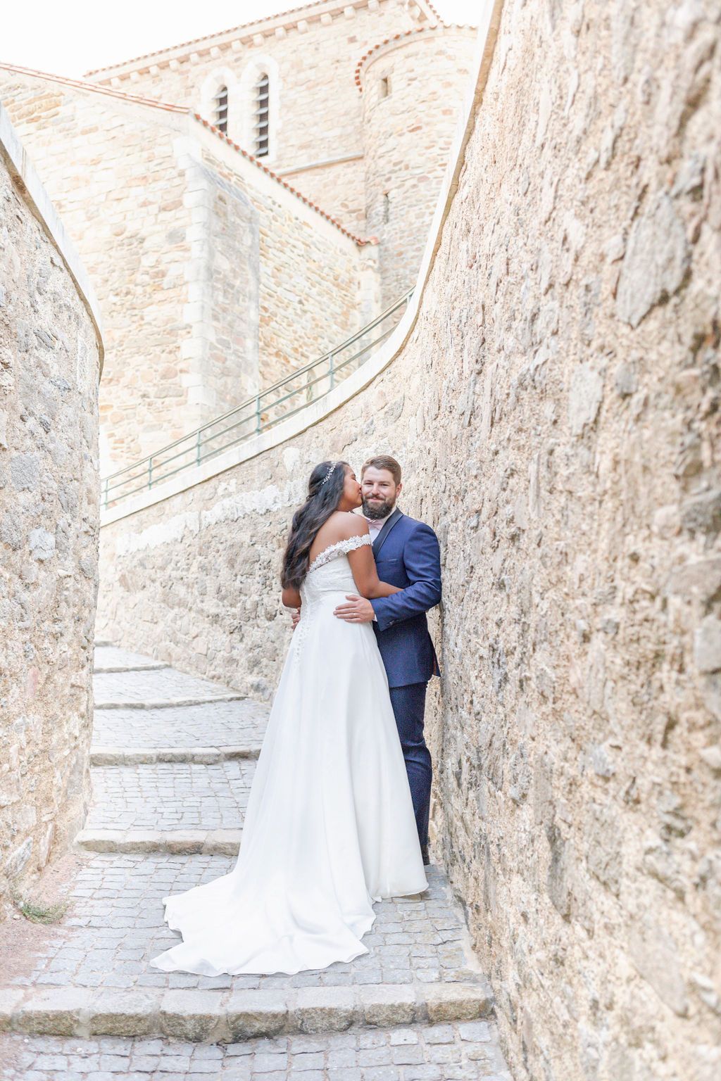 Newlyweds share intimate moment on rustic stone stairway.