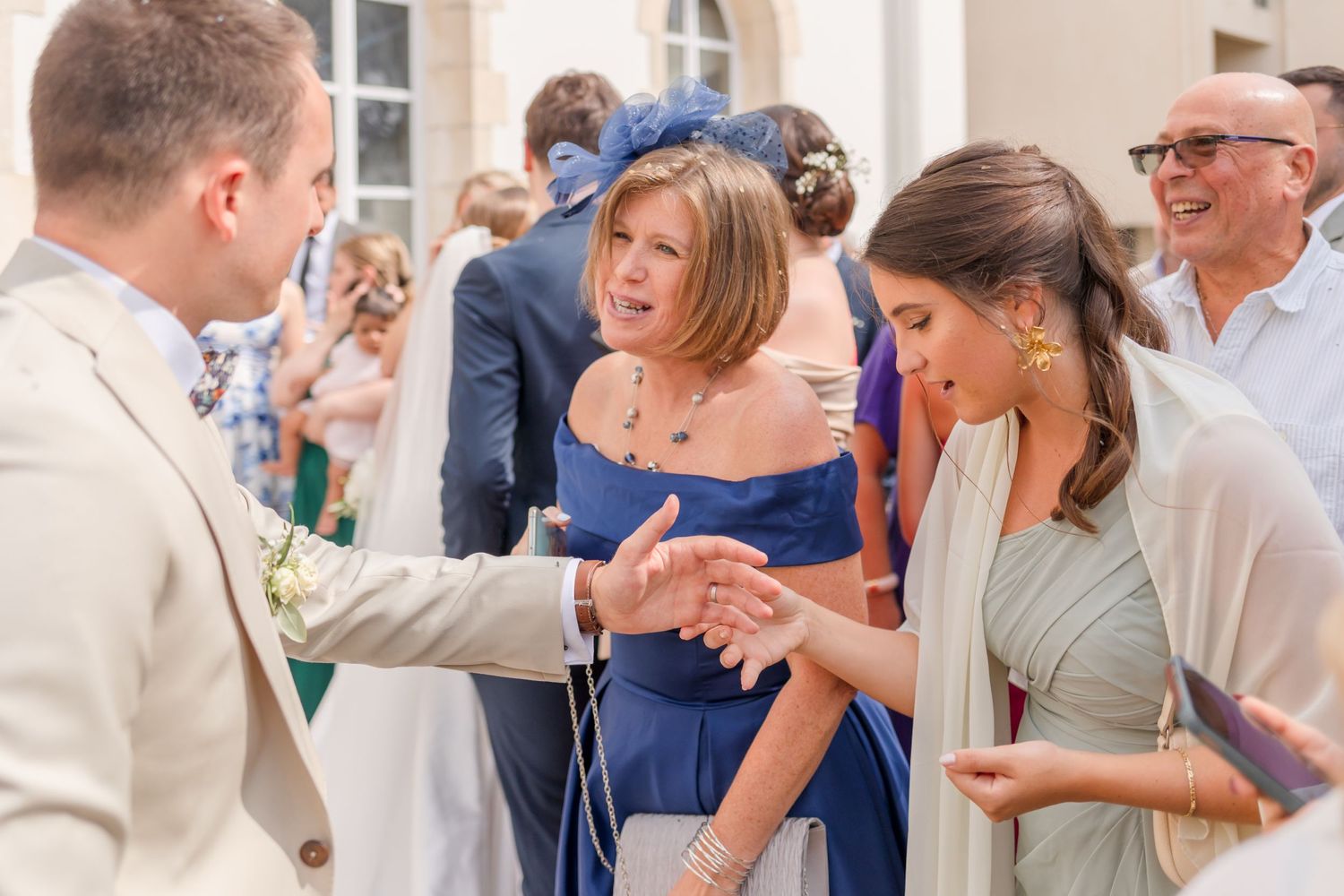 Guests in formal attire mingle and chat during an outdoor wedding reception.