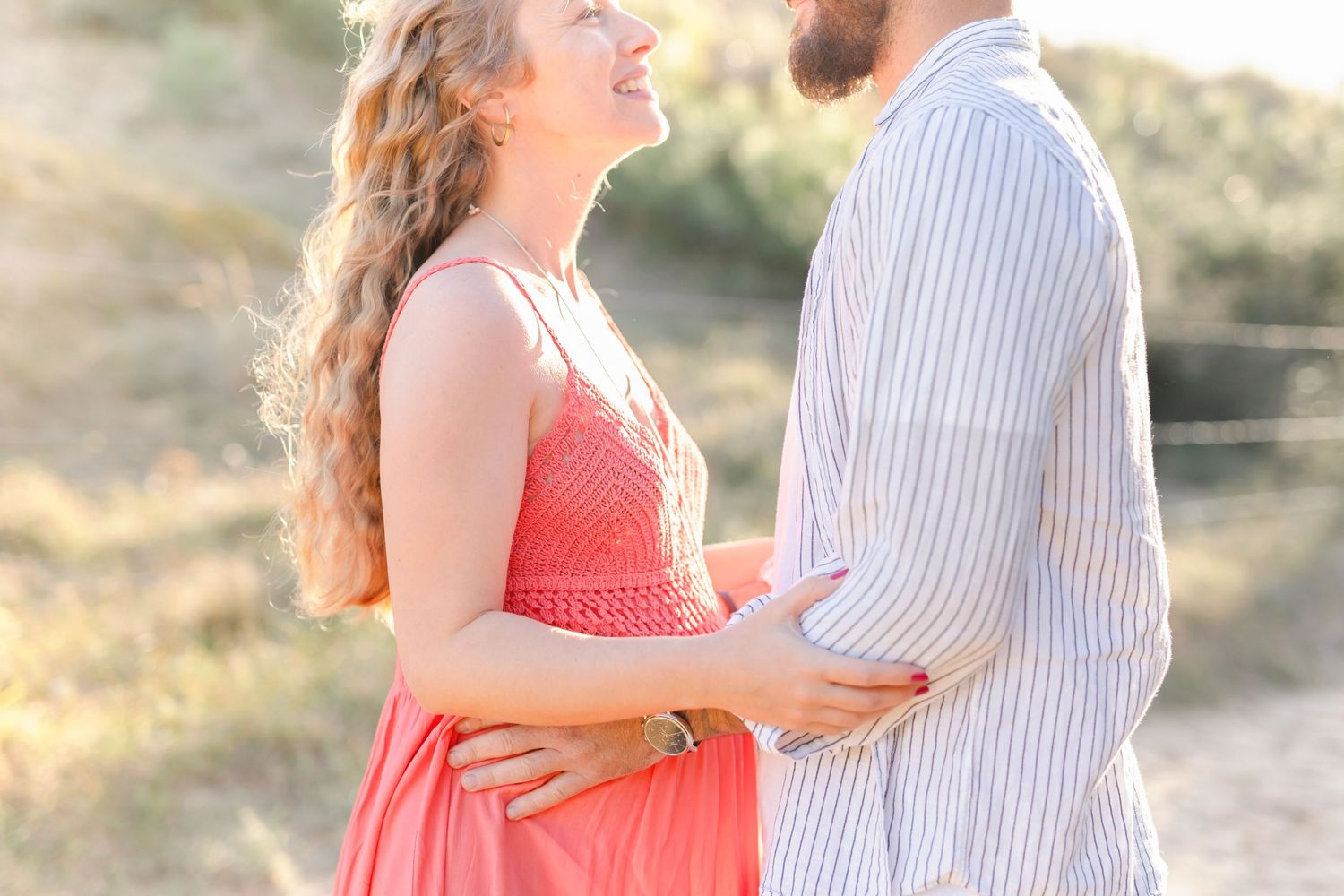 A loving embrace captured during a golden hour outdoor maternity photo session.