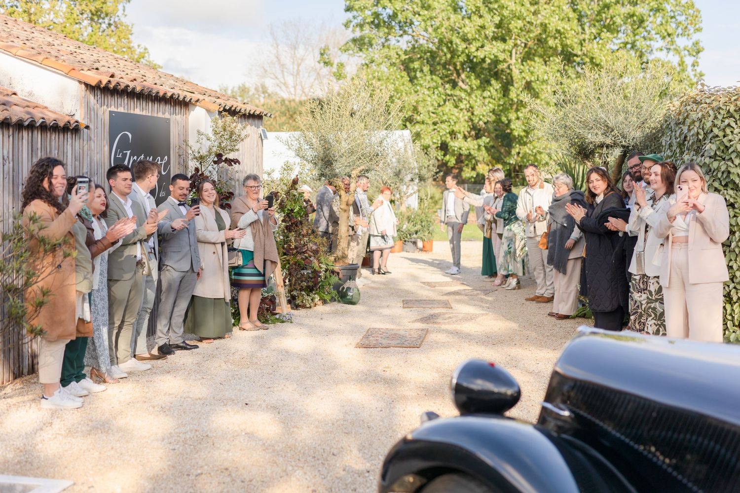 Wedding guests standing in line outside a venue with terra cotta tile roof.