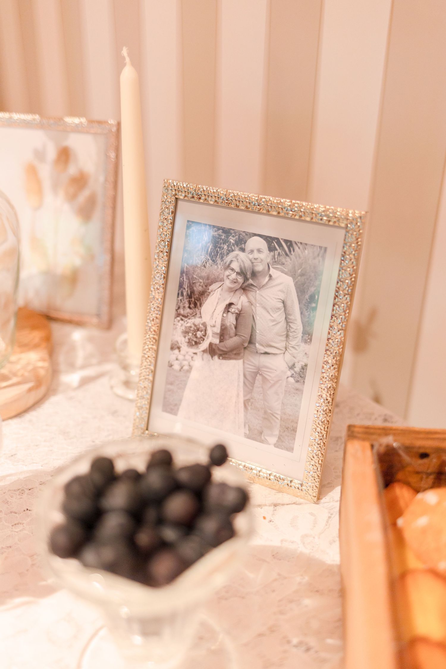 Vintage framed wedding photograph displayed with candles and decorative elements on a white surface.