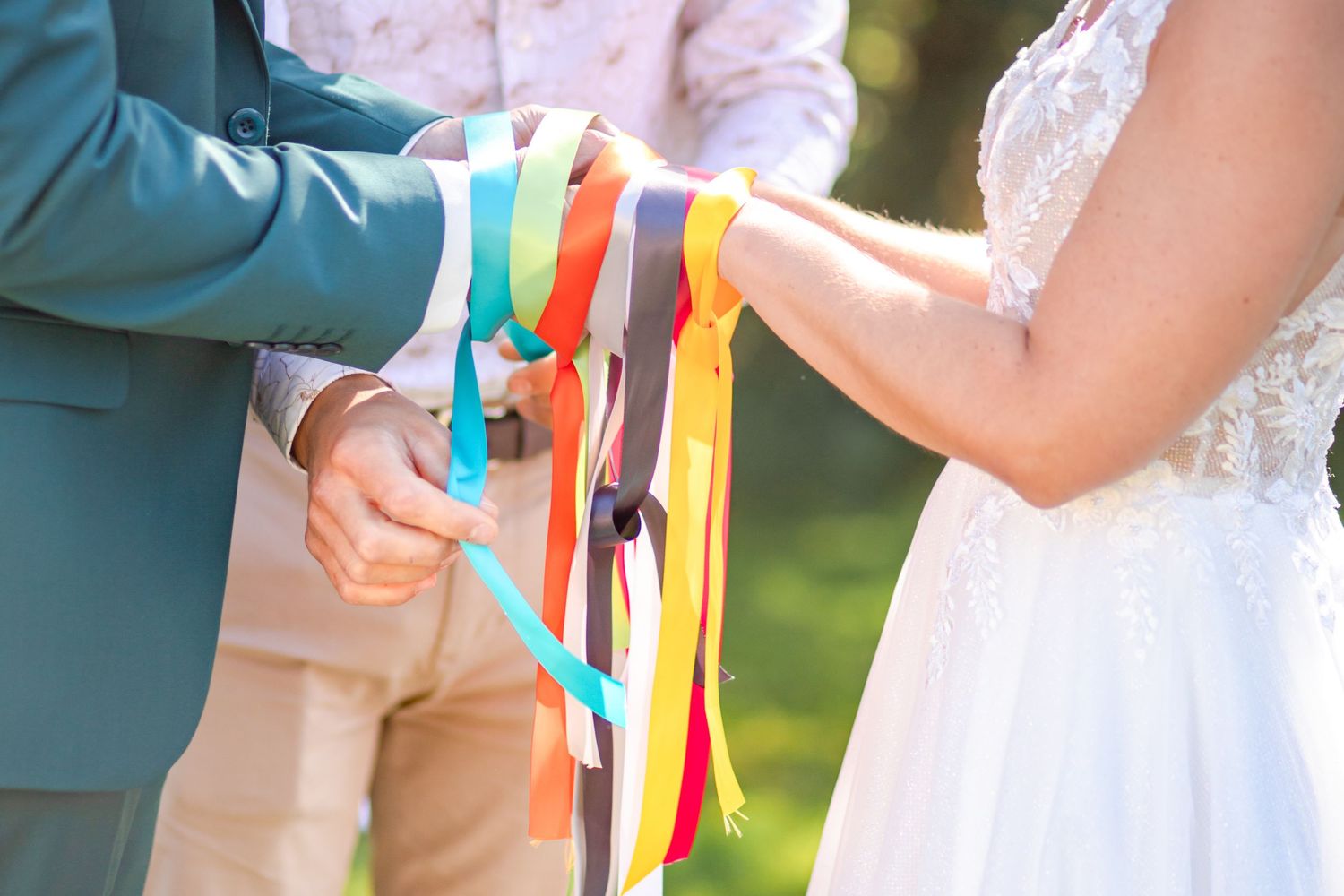 A celebratory outdoor scene showing colorful ribbons being held during a wedding ceremony.