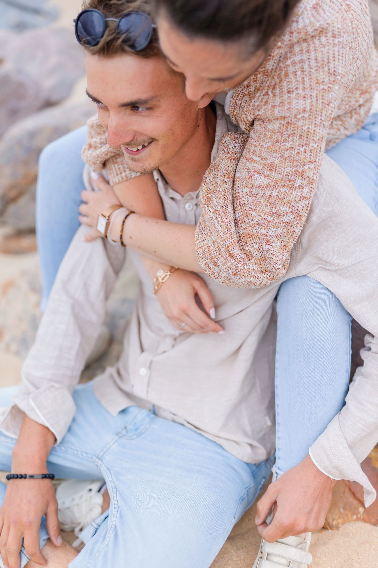 Intimate moment captured of a couple in casual clothing sitting close together on the beach.