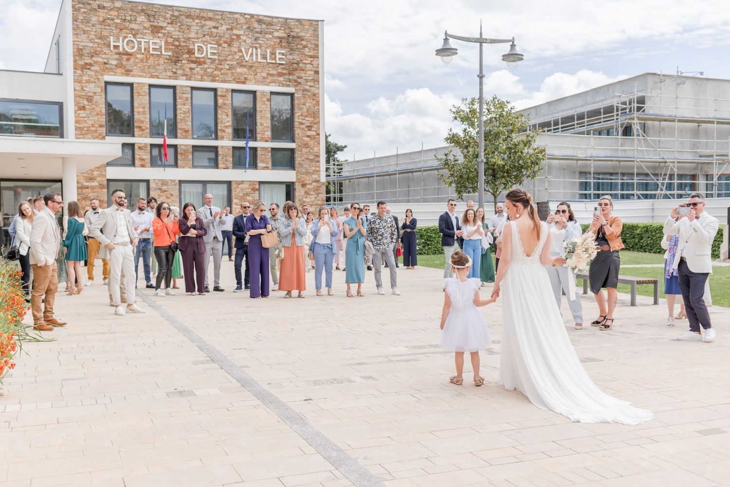 Panoramic view of wedding celebration outside classic brick architecture.