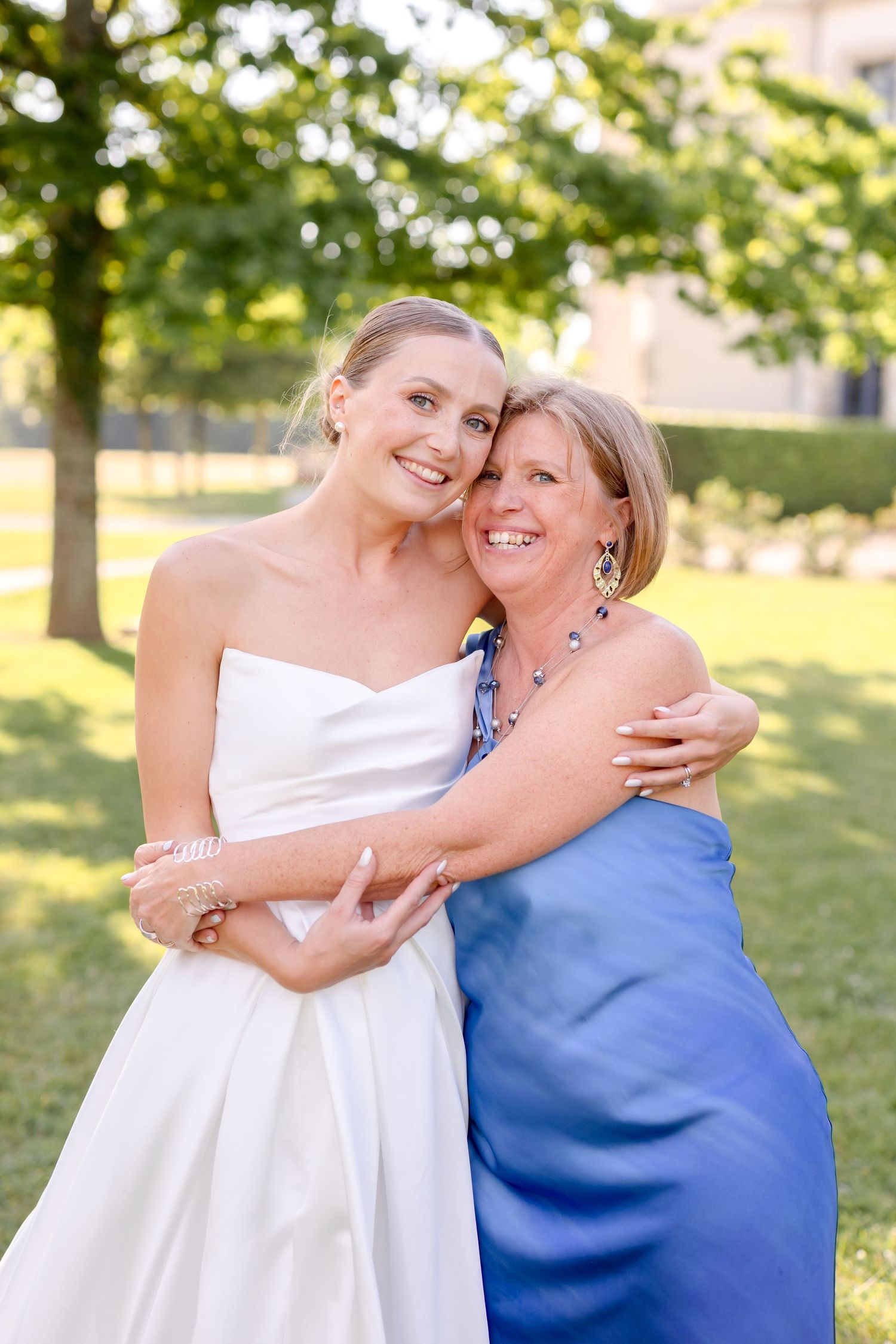 Joyful wedding day embrace captured on sunny lawn with castle in background.