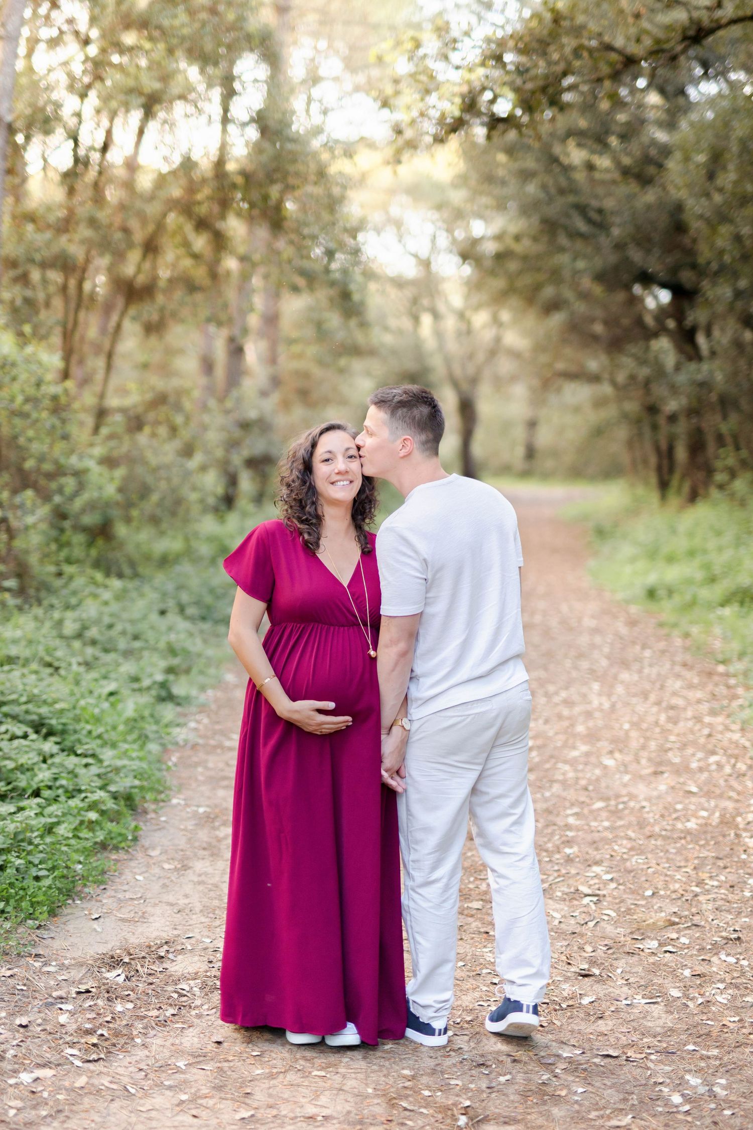 Sweet maternity session photographs on a leaf-strewn path with golden hour lighting.