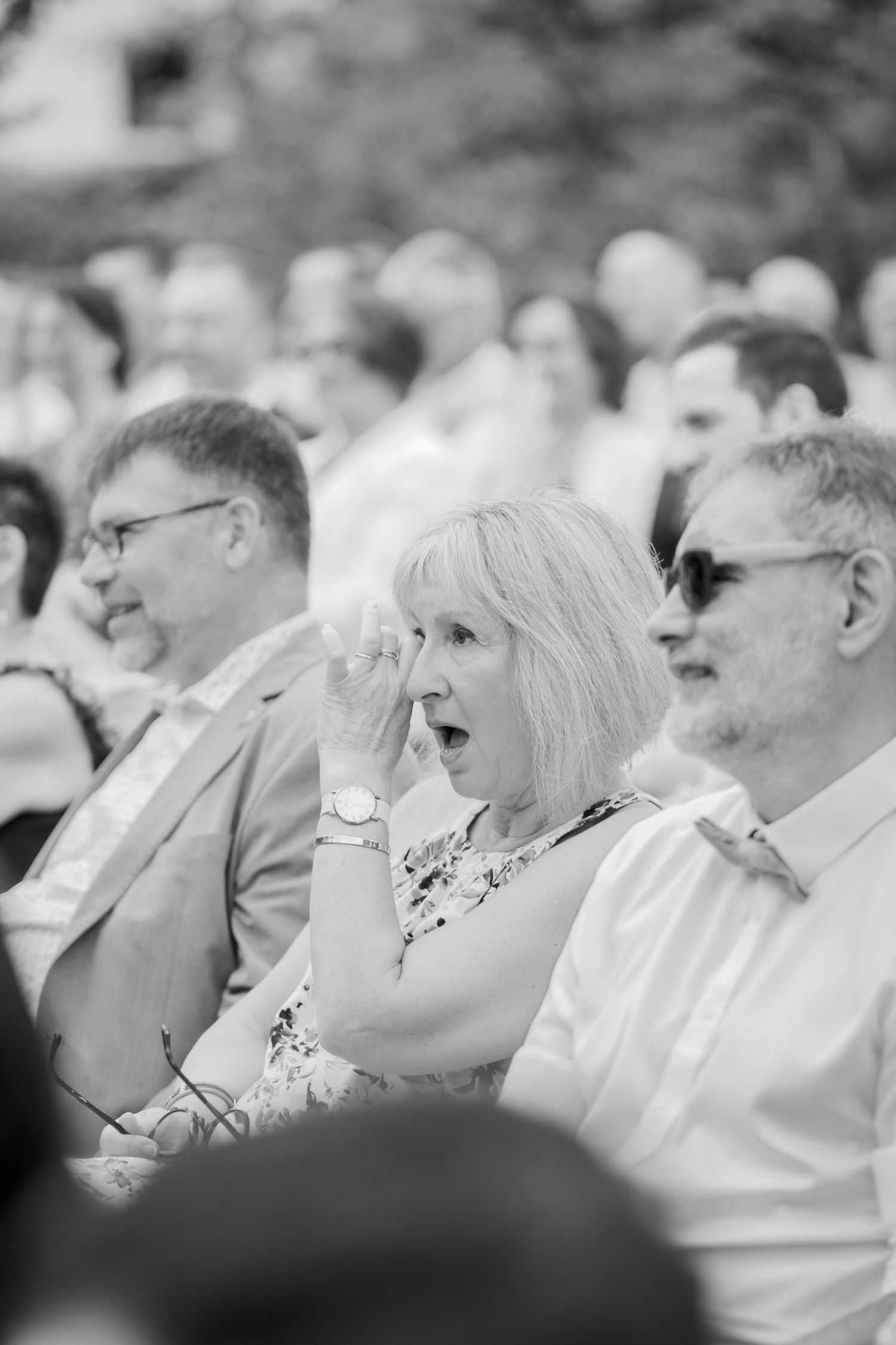 Black and white photo of wedding guests watching ceremony with expressions of joy.