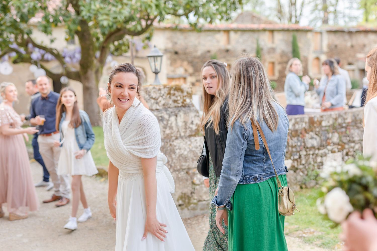 Wedding guests socializing in a charming courtyard surrounded by historic stone buildings.