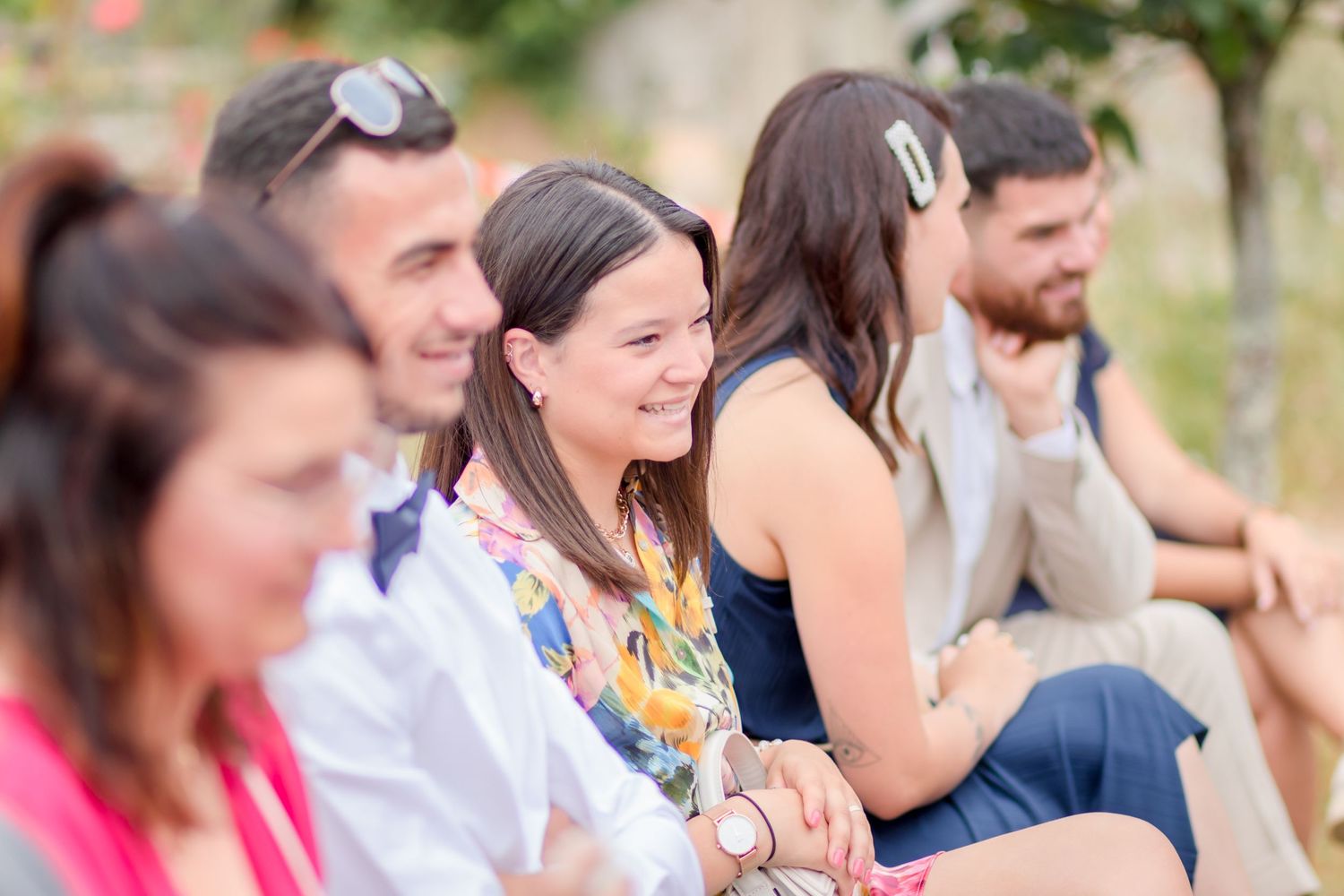 Wedding guests smiling and enjoying outdoor ceremony seating area.