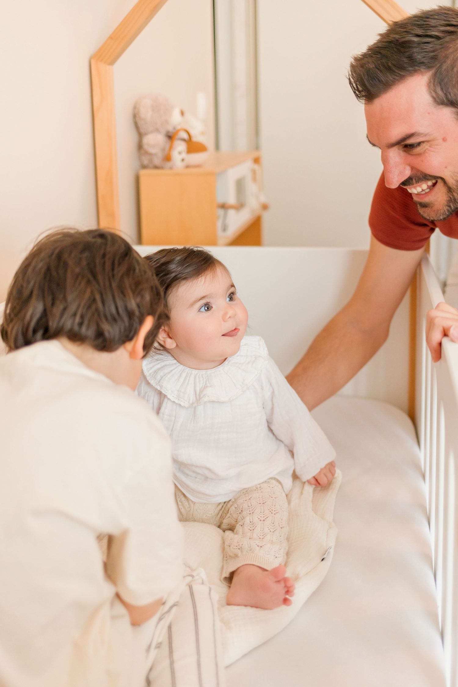 Family interaction around white crib with warm lighting.