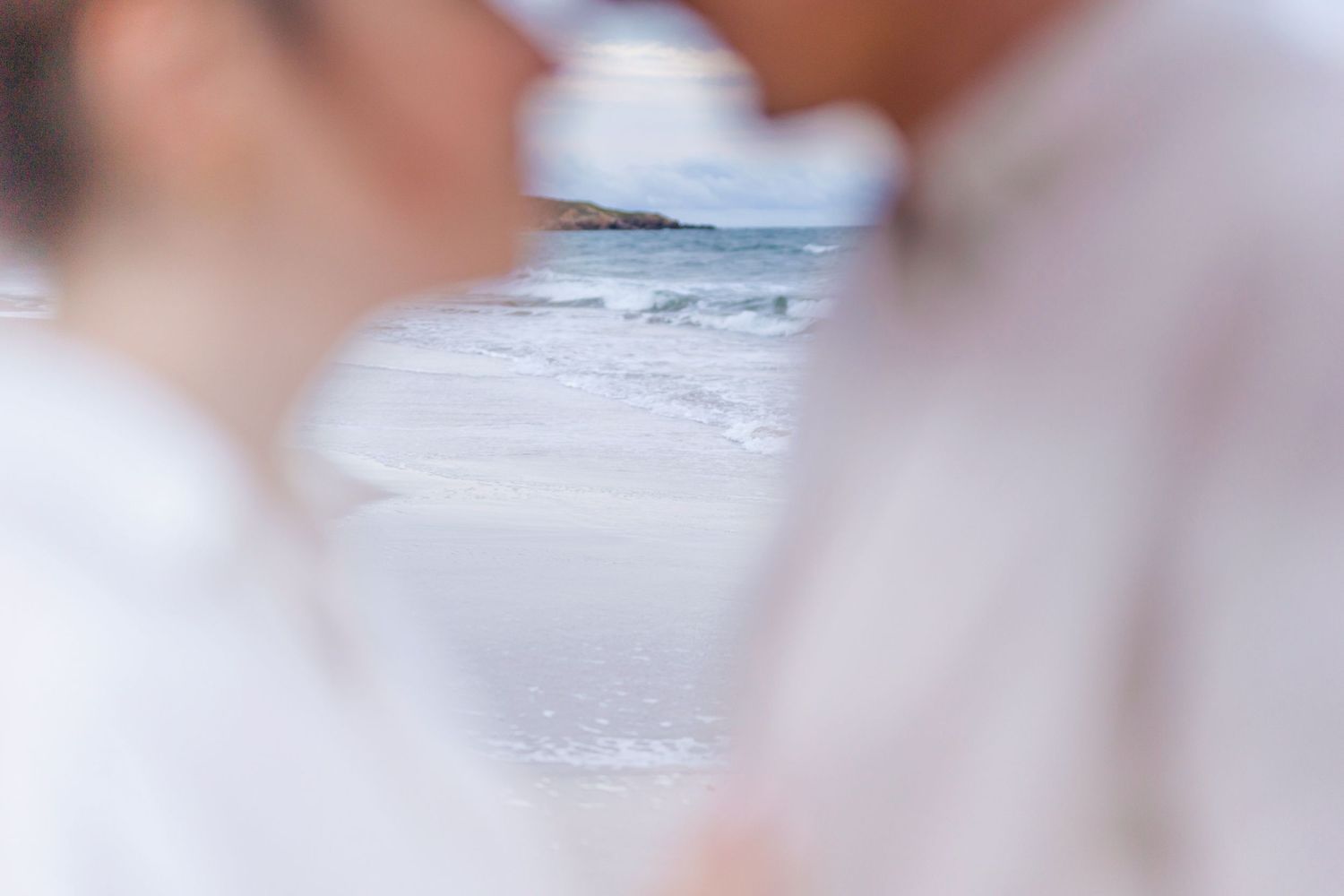 A blurred beach scene with ocean waves visible in the background.