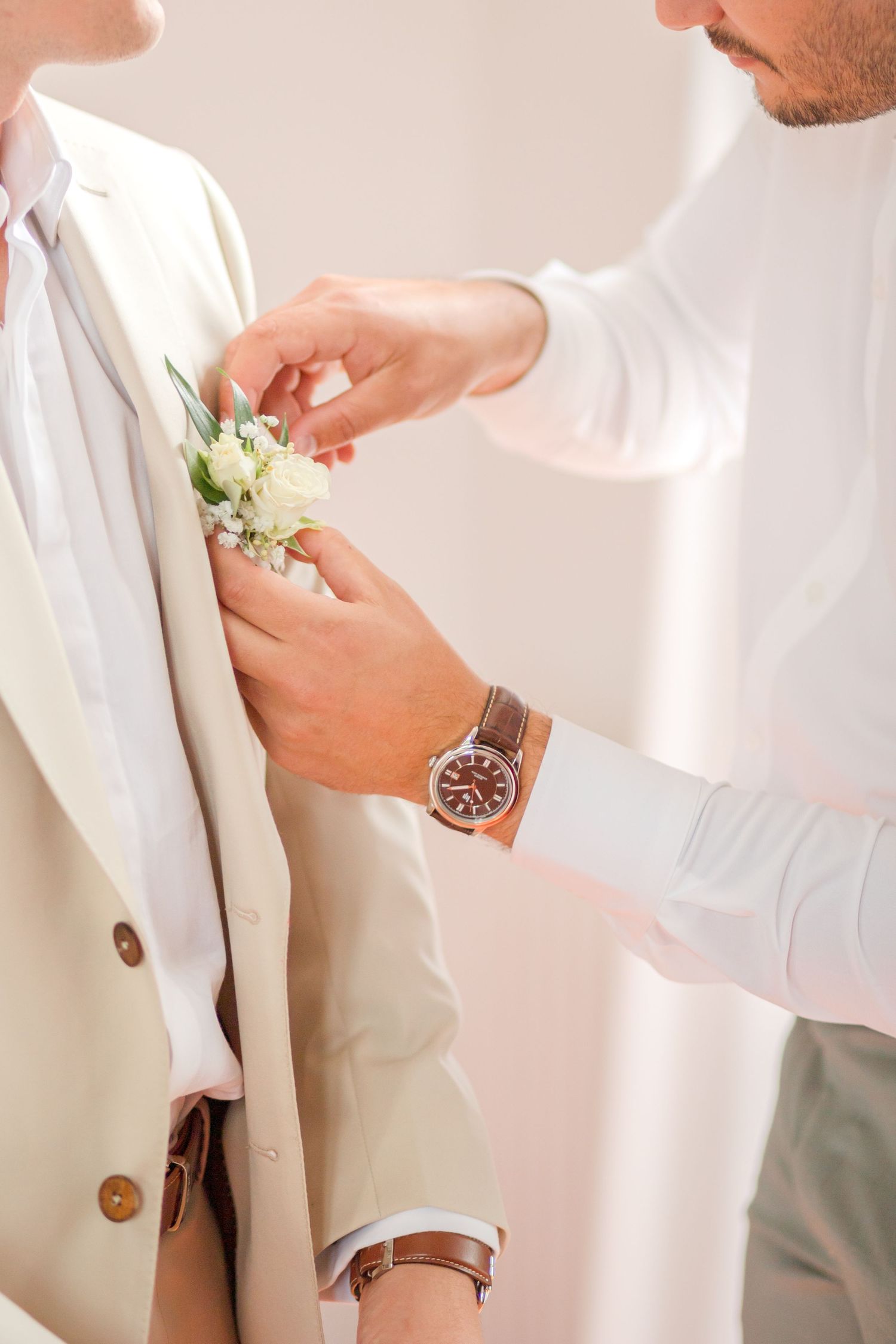 Wedding preparation details showing formal attire and boutonniere pinning.